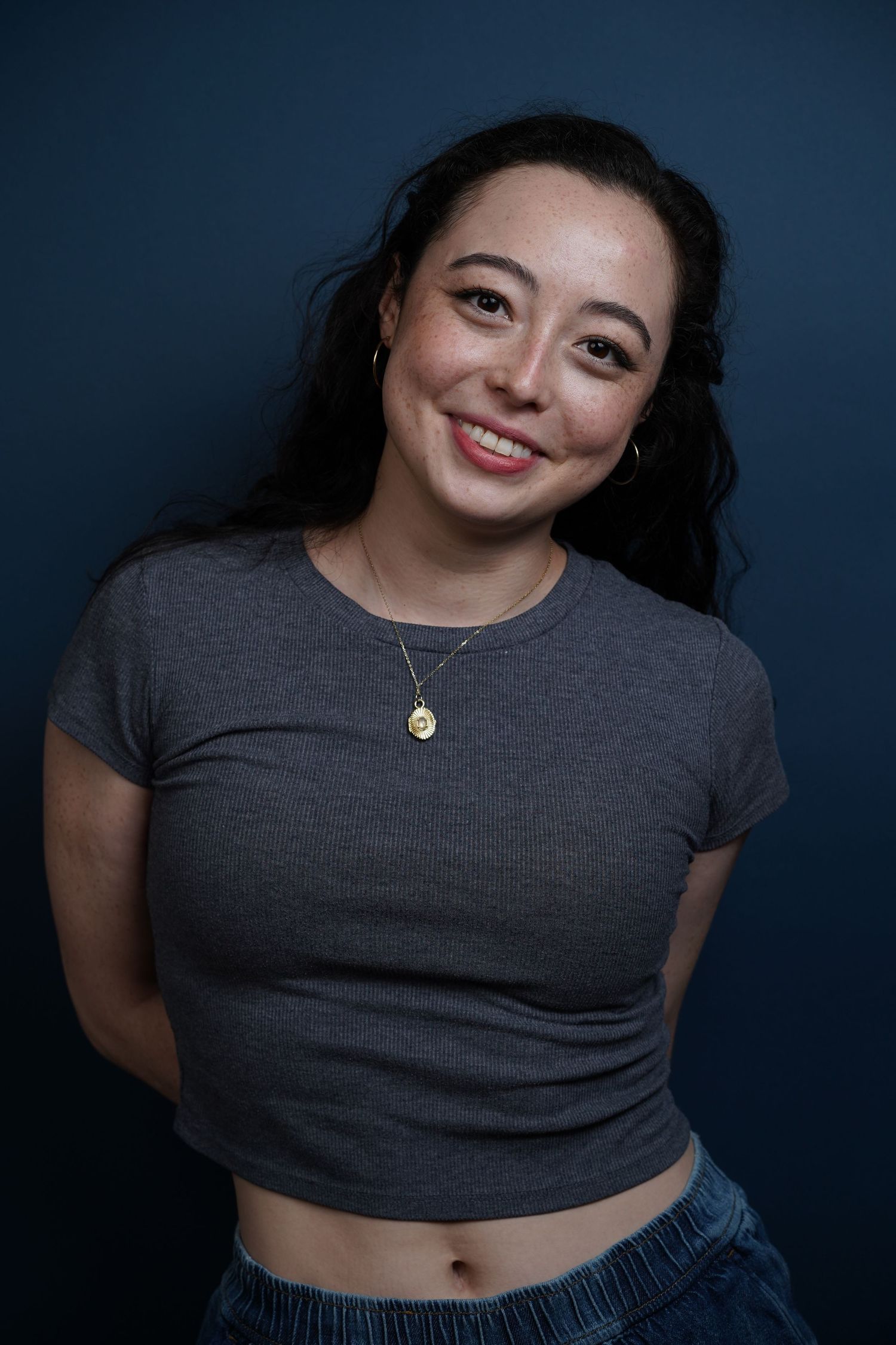 A series of five portrait photos showing someone in a gray top against a dark background with changing poses and expressions.