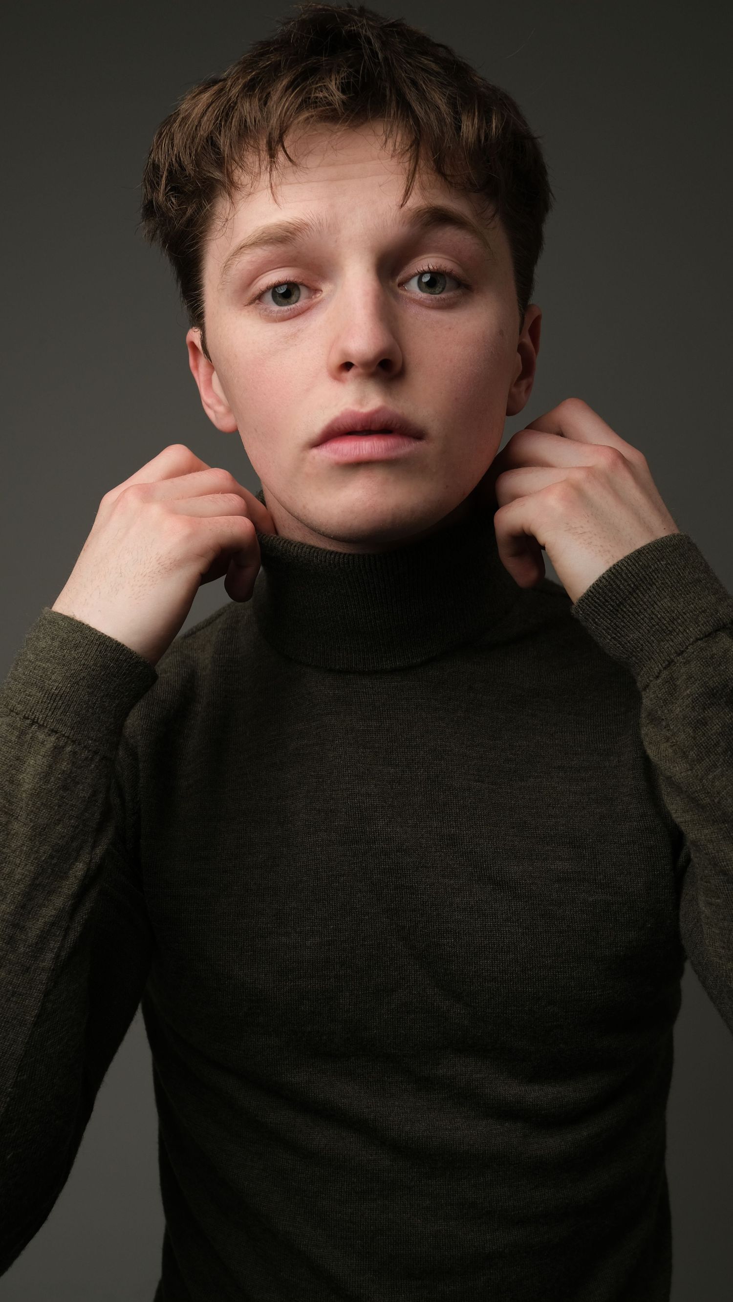 A series of portrait shots showing poses in an olive green sweater against a gray backdrop.