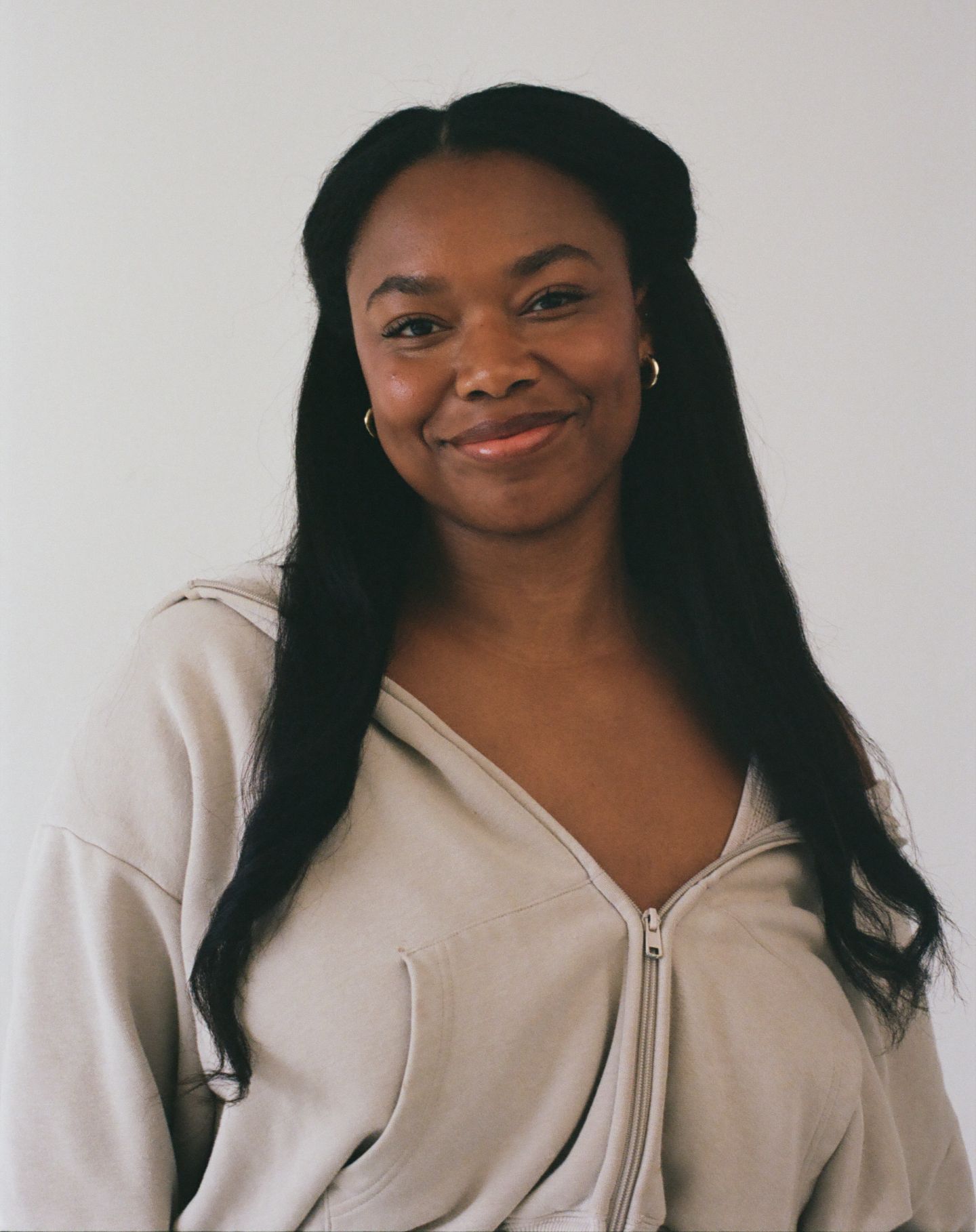 Four similar photos of someone wearing a white zippered knit sweater while posing against a neutral background.