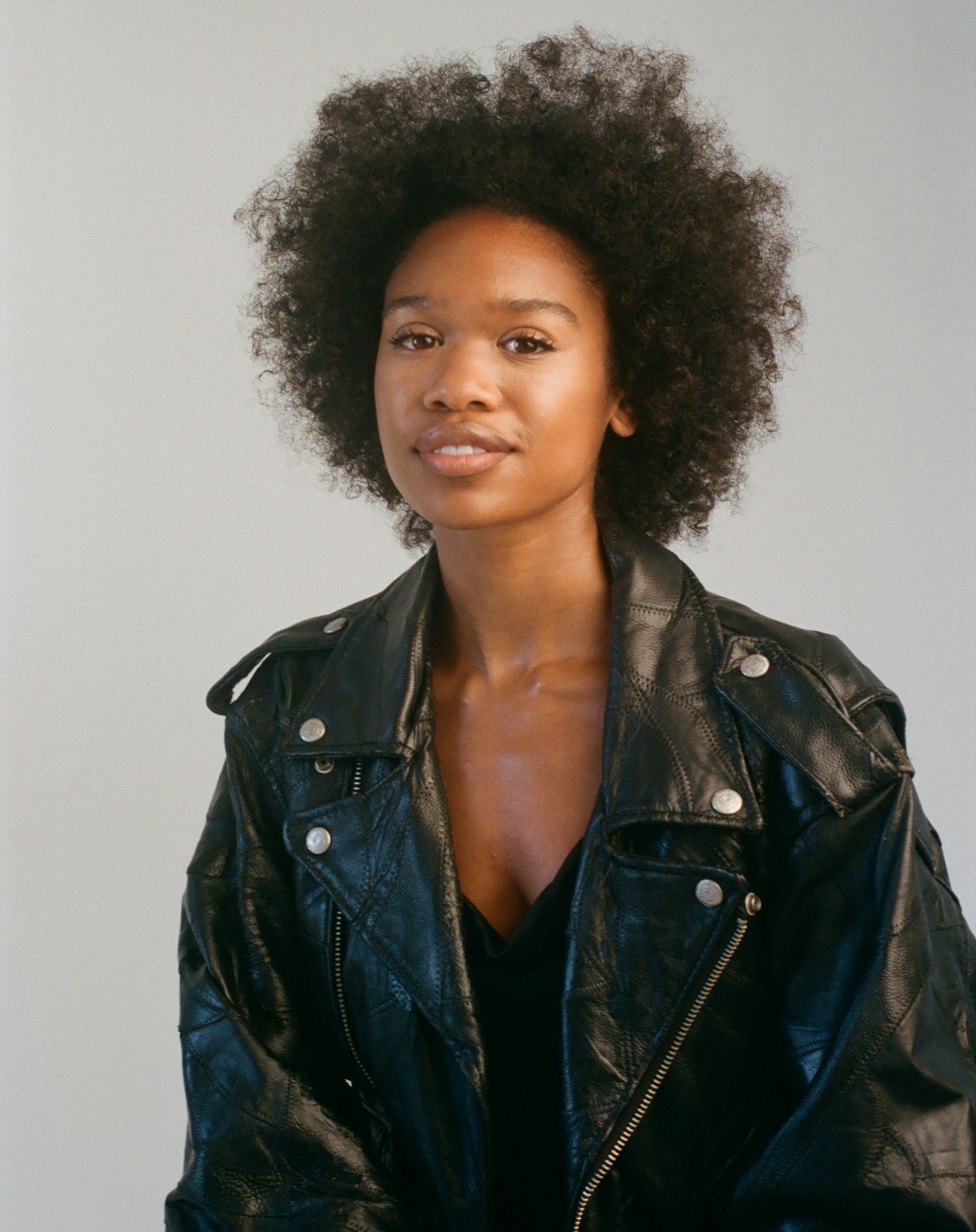 Four headshot portraits featuring natural afro hairstyle and black leather jacket in studio lighting.