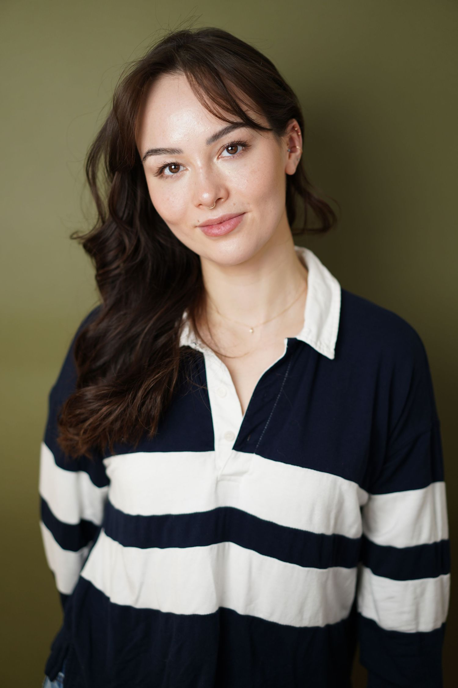 Professional headshot of someone wearing a navy and white striped rugby style shirt against a green background.