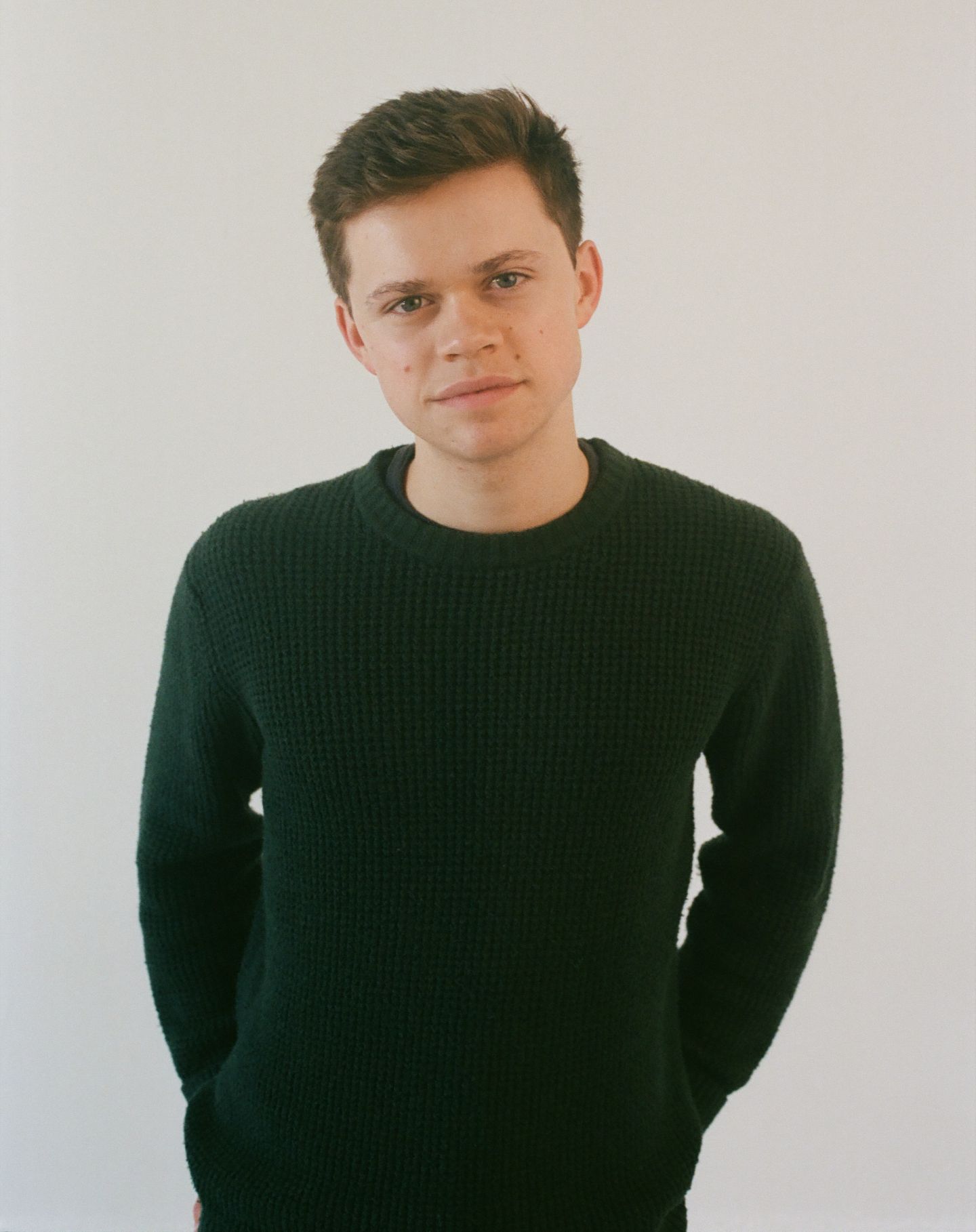 A sequence of photos showing someone wearing a dark knit sweater against a white background posing with subtle head movements.