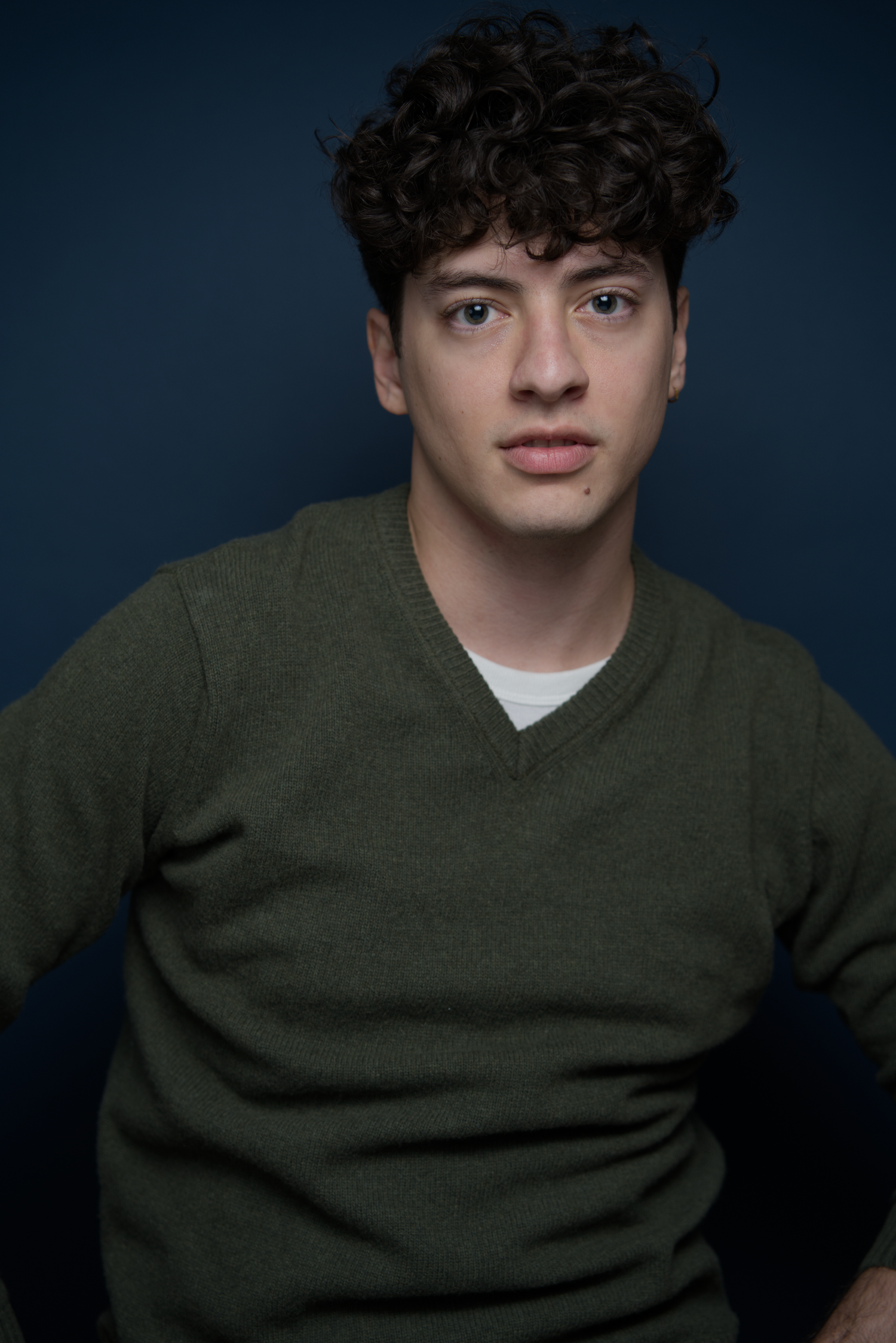Portrait series showing someone in a dark green sweater against a deep blue background in various poses.