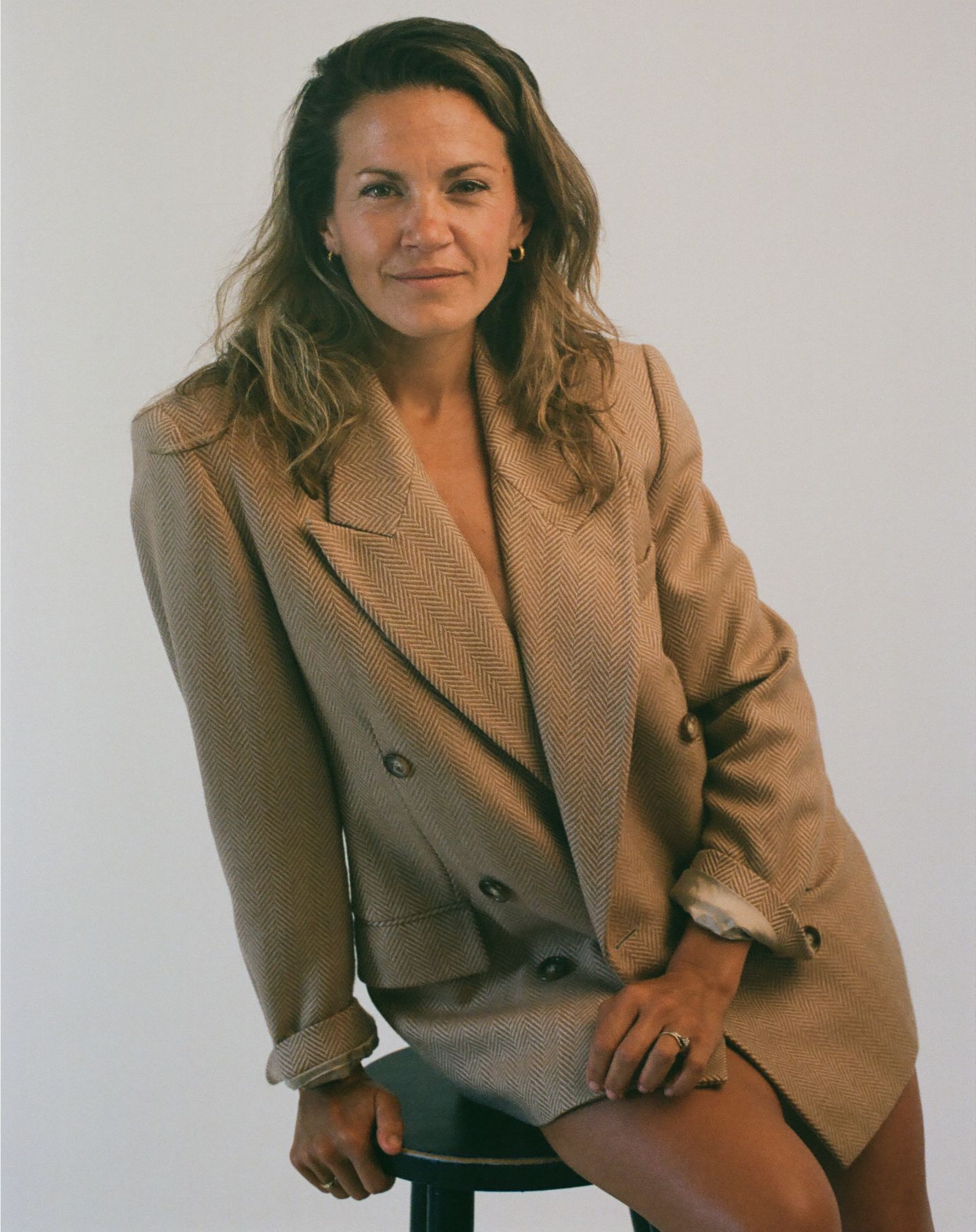 A figure wearing a tan blazer poses casually in a series of vintage-style photographs against a light background.