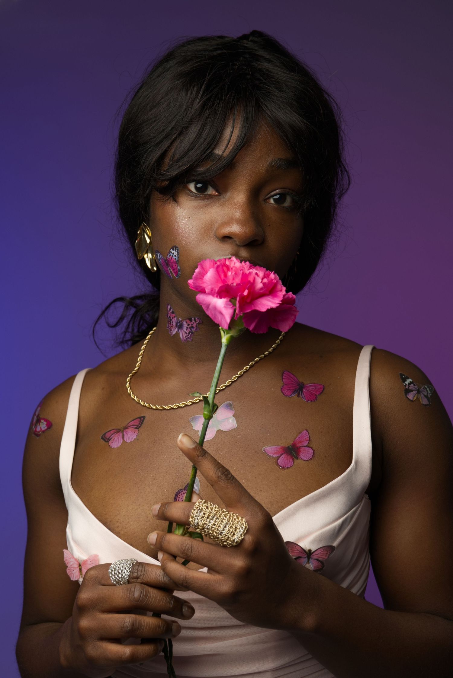 A series of artistic portraits against a purple background featuring pink flowers and butterfly decorations.