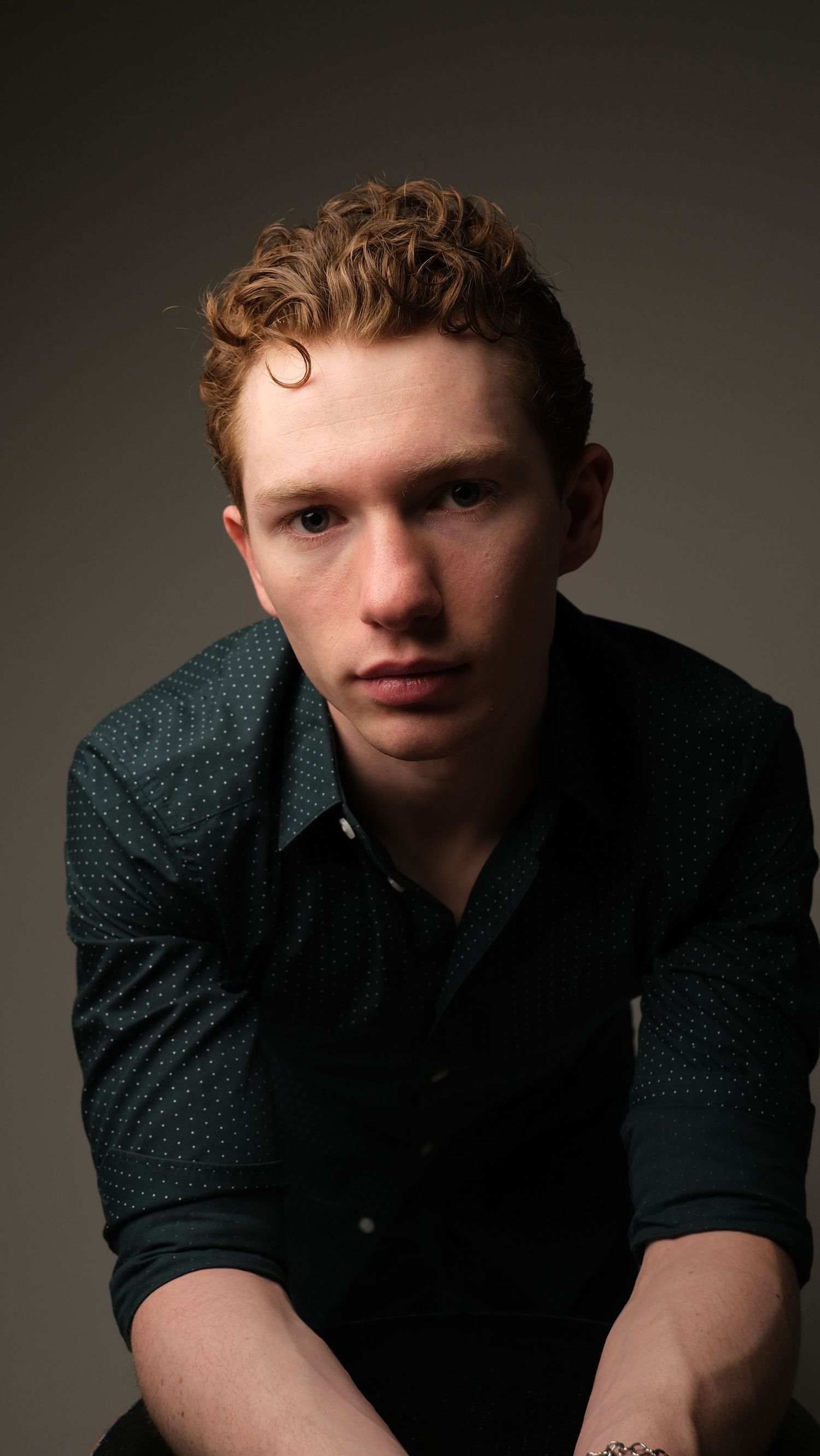 A series of four portraits showing someone wearing a dark shirt against a neutral background in moody lighting.