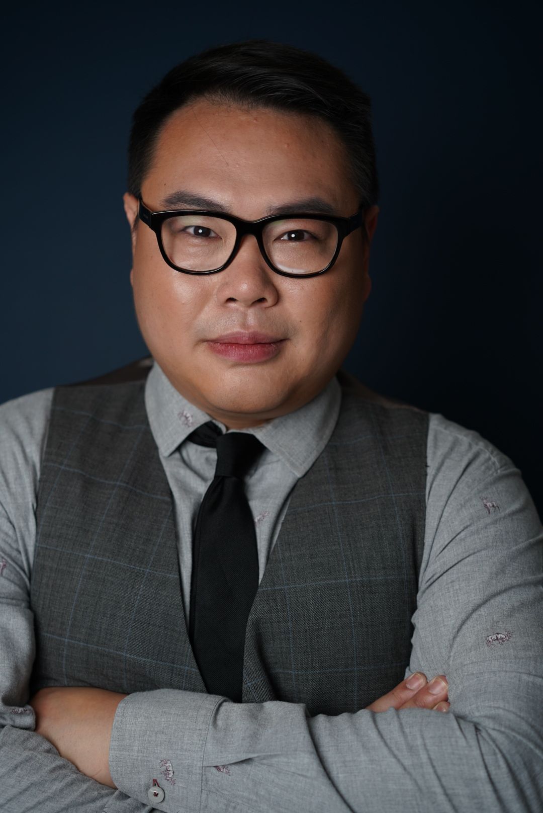 Professional headshot series showing person in gray suit and black tie against dark background.