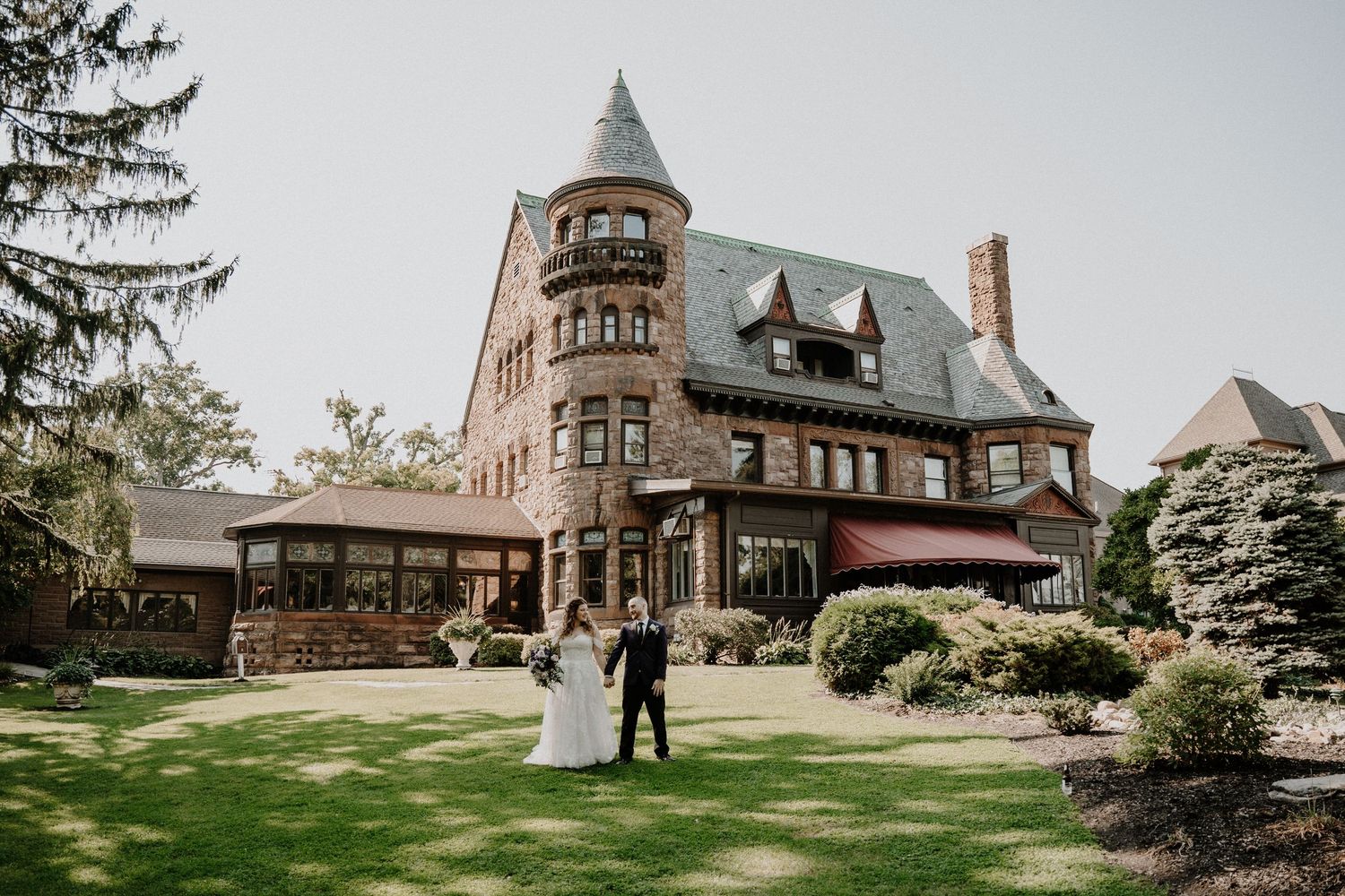 Wedding ceremony outside historic Victorian mansion with manicured gardens. Belhurst Castle, Geneva NY