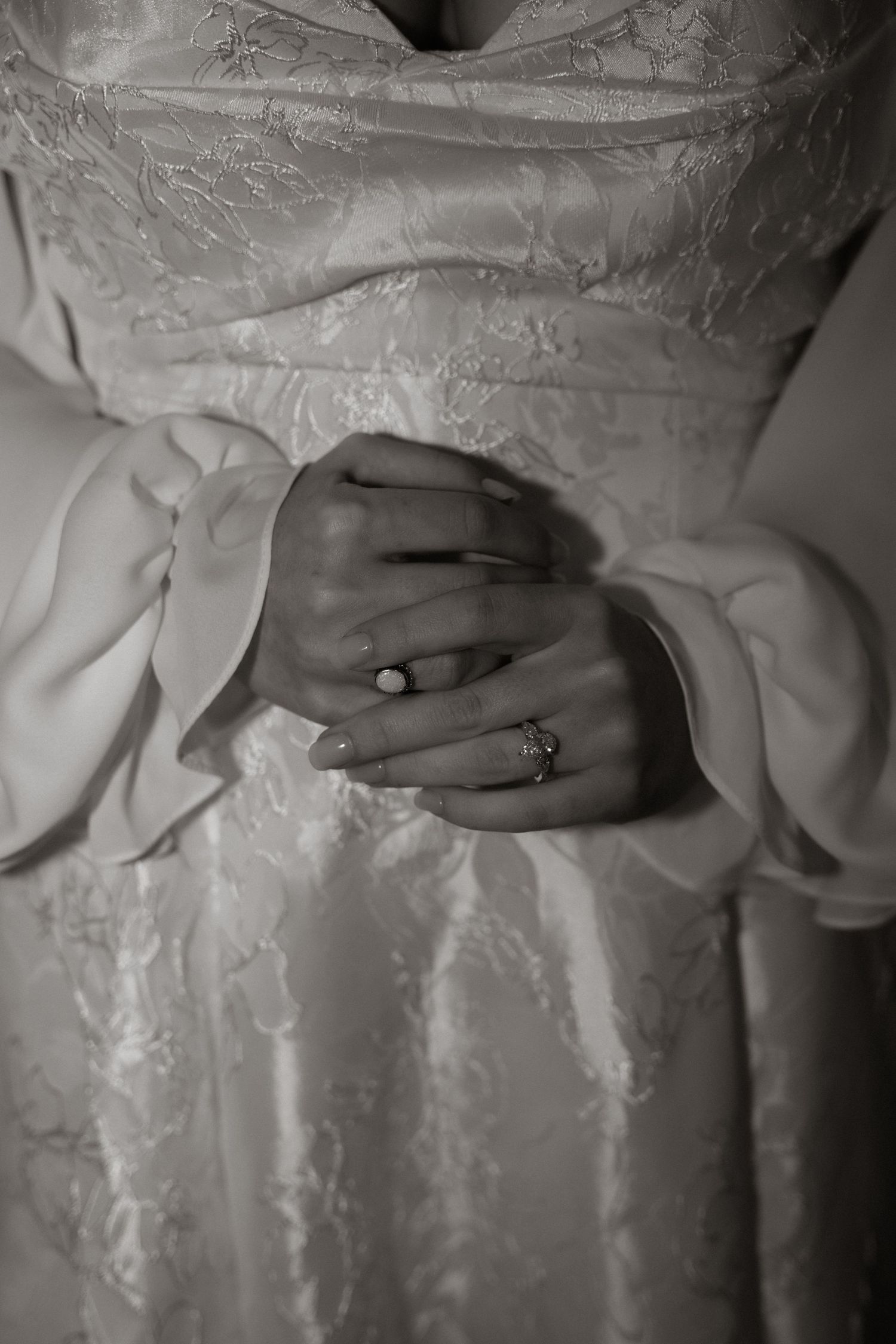 Close-up black and white photos of hands wearing wedding rings against white lace fabric in sequence.