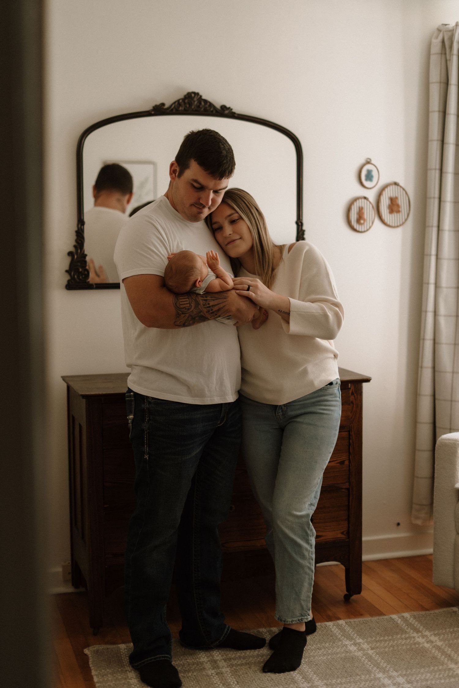 A couple dances intimately together in a dimly lit room with hardwood floors and white walls.