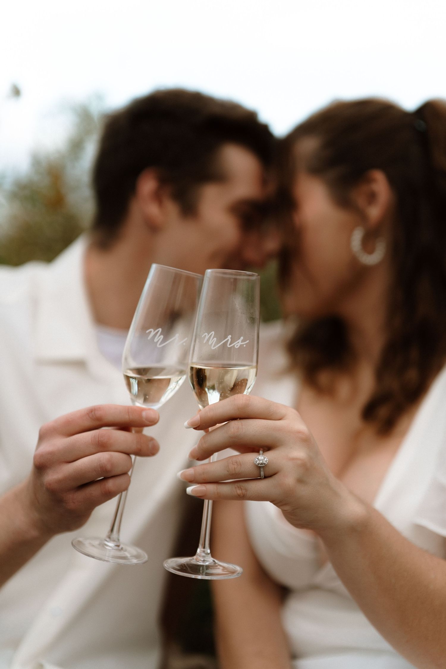 Two champagne glasses clink together in celebration at a wedding reception.