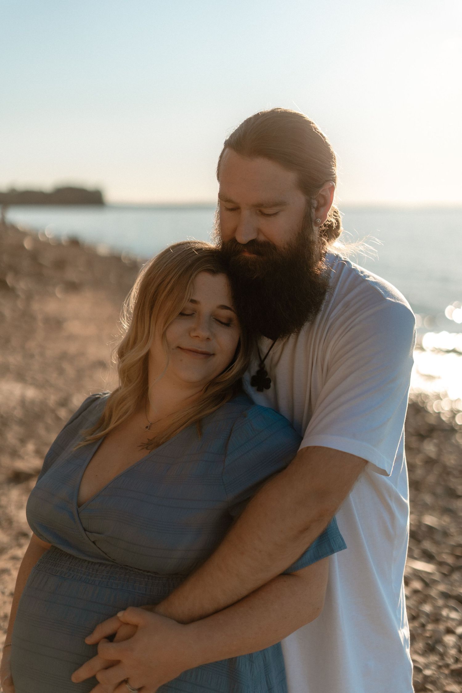 A couple shares tender moments together on a rocky beach at sunset, embracing and laughing in a series of candid shots.