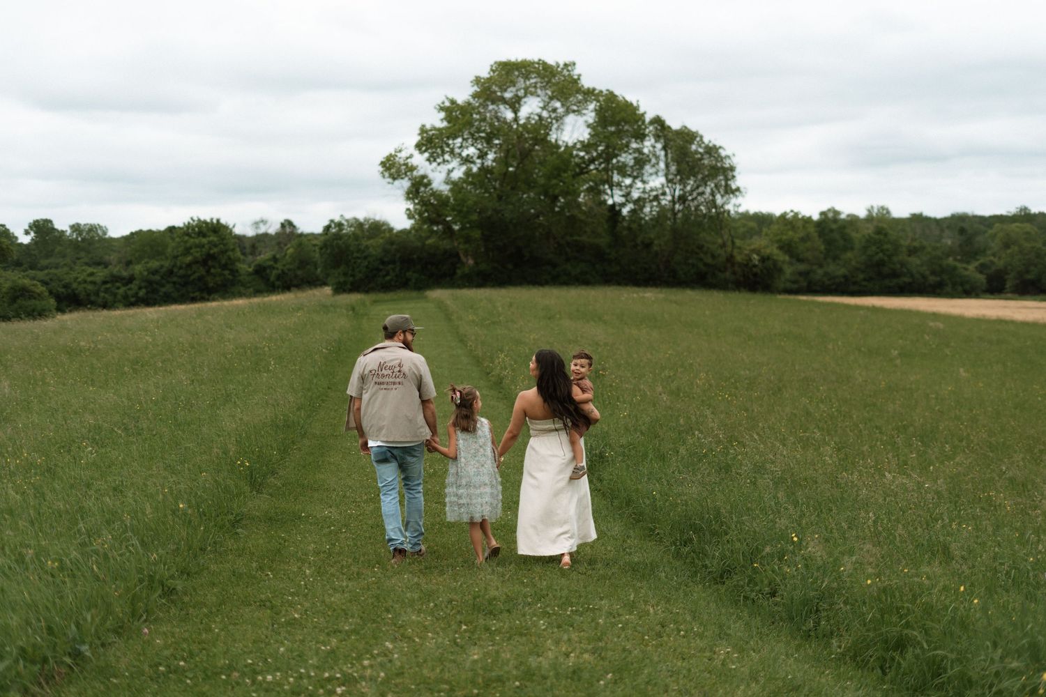 A couple walks through a lush green hillside meadow during a romantic countryside photo session.