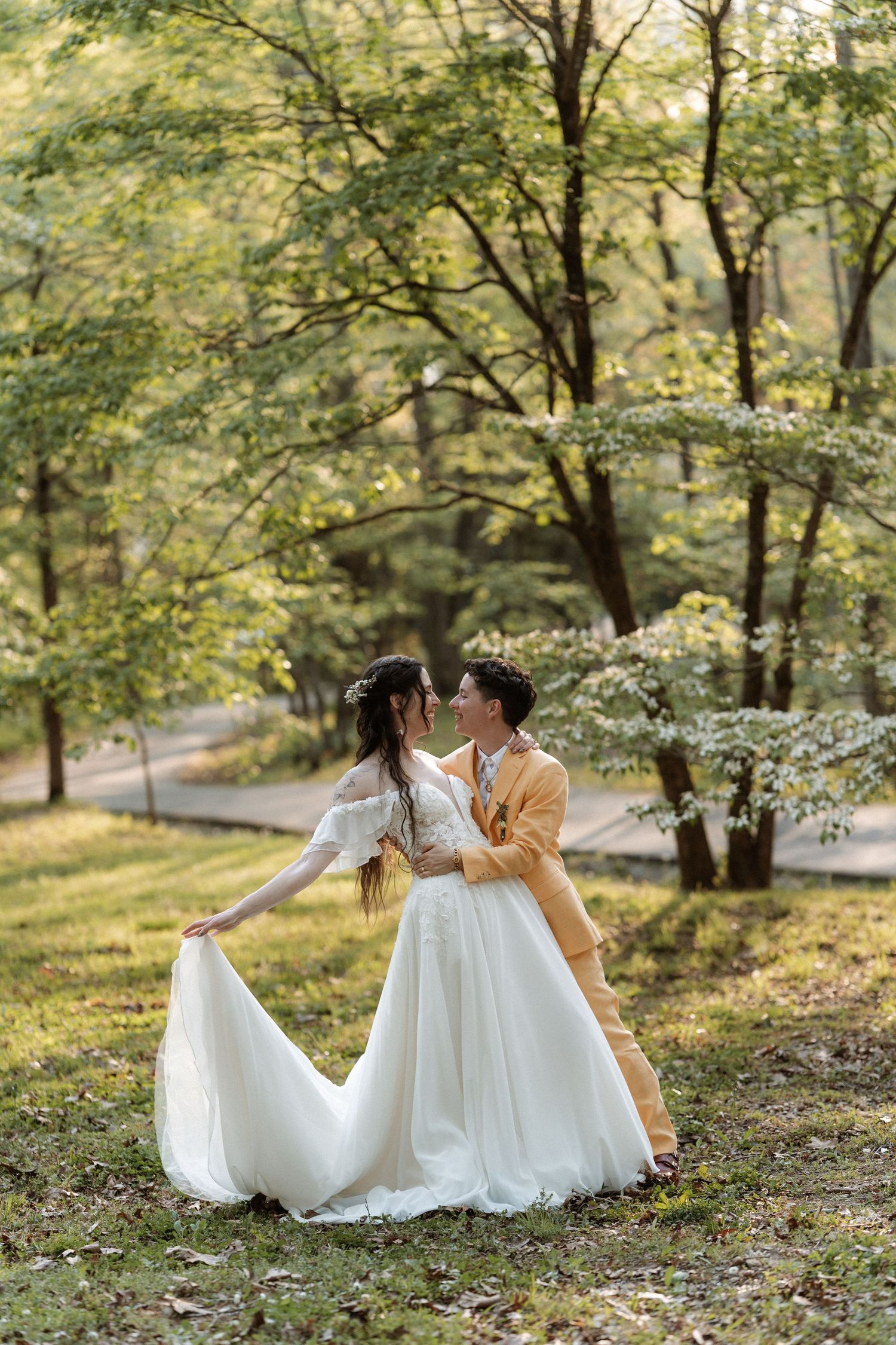 Bride and groom share a romantic moment in a lush green park, with the bride in a flowing white gown.