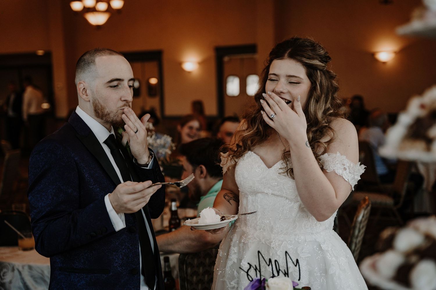 Couple sharing an emotional moment while eating cake at their wedding reception.