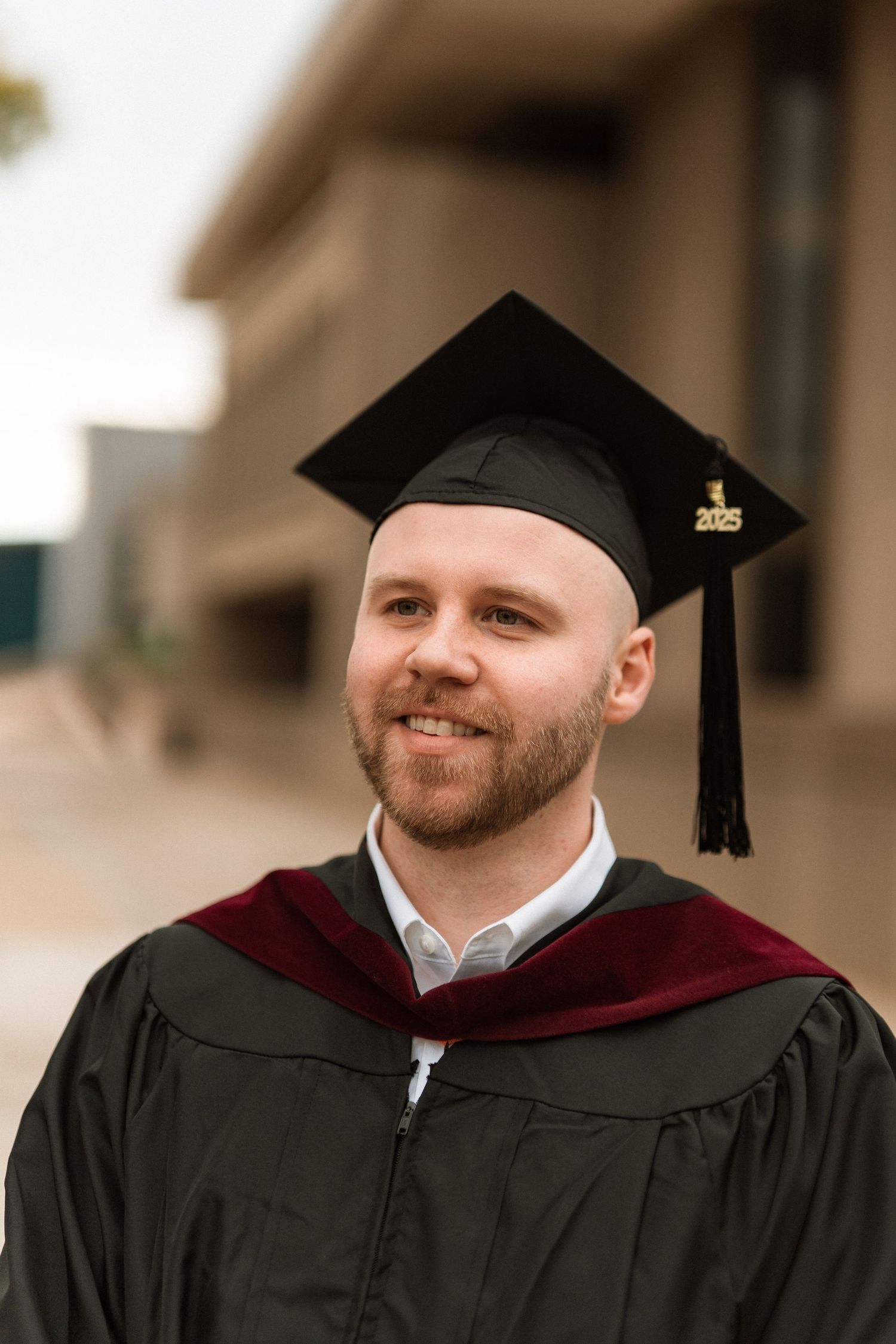 Graduate wearing black cap and burgundy gown smiles in three similar portraits during commencement ceremony.
