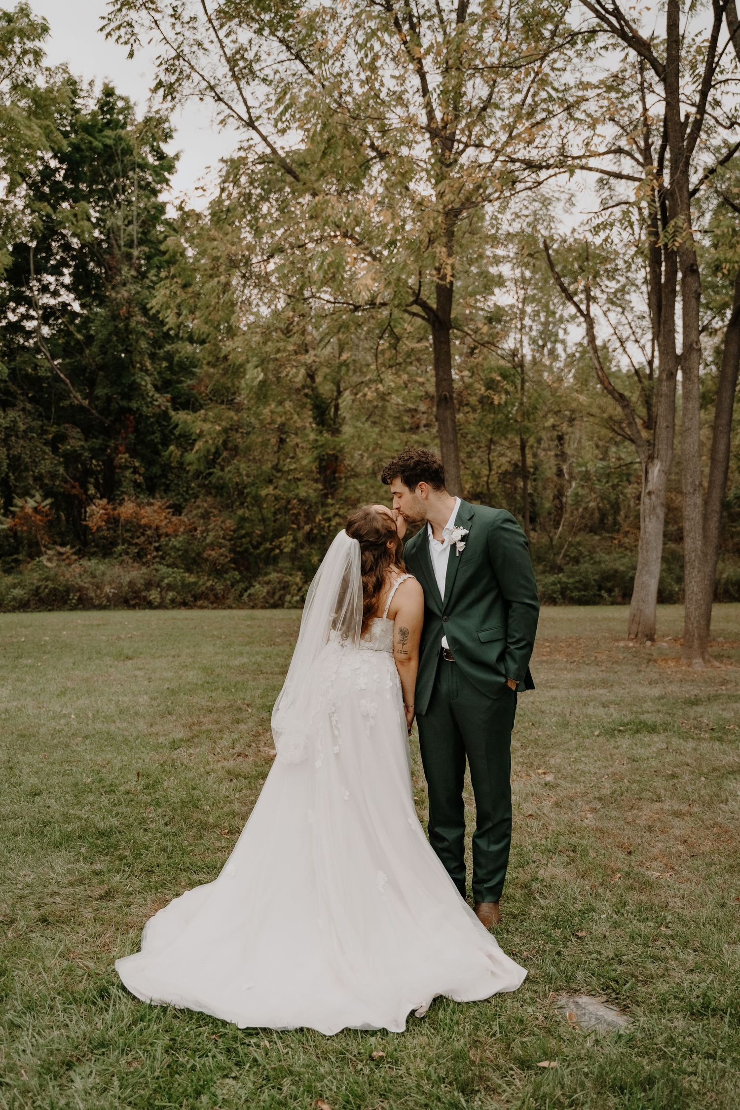 Romantic wedding portrait of couple sharing intimate moment in autumn woodland setting.