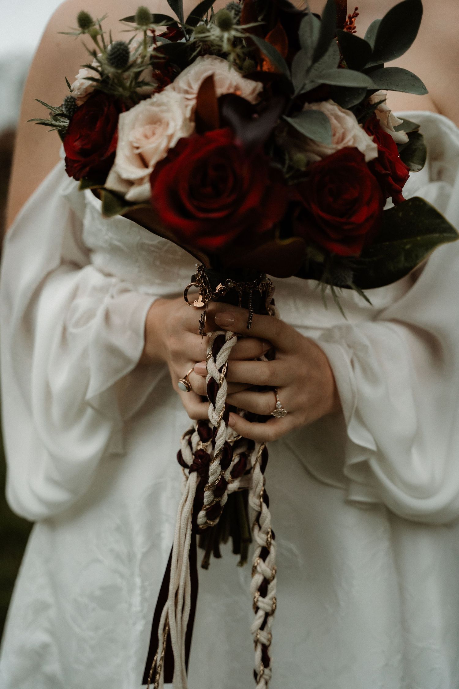 A series of close-up shots showing hands holding a dramatic bouquet of dark red roses and white flowers with trailing ribbons.