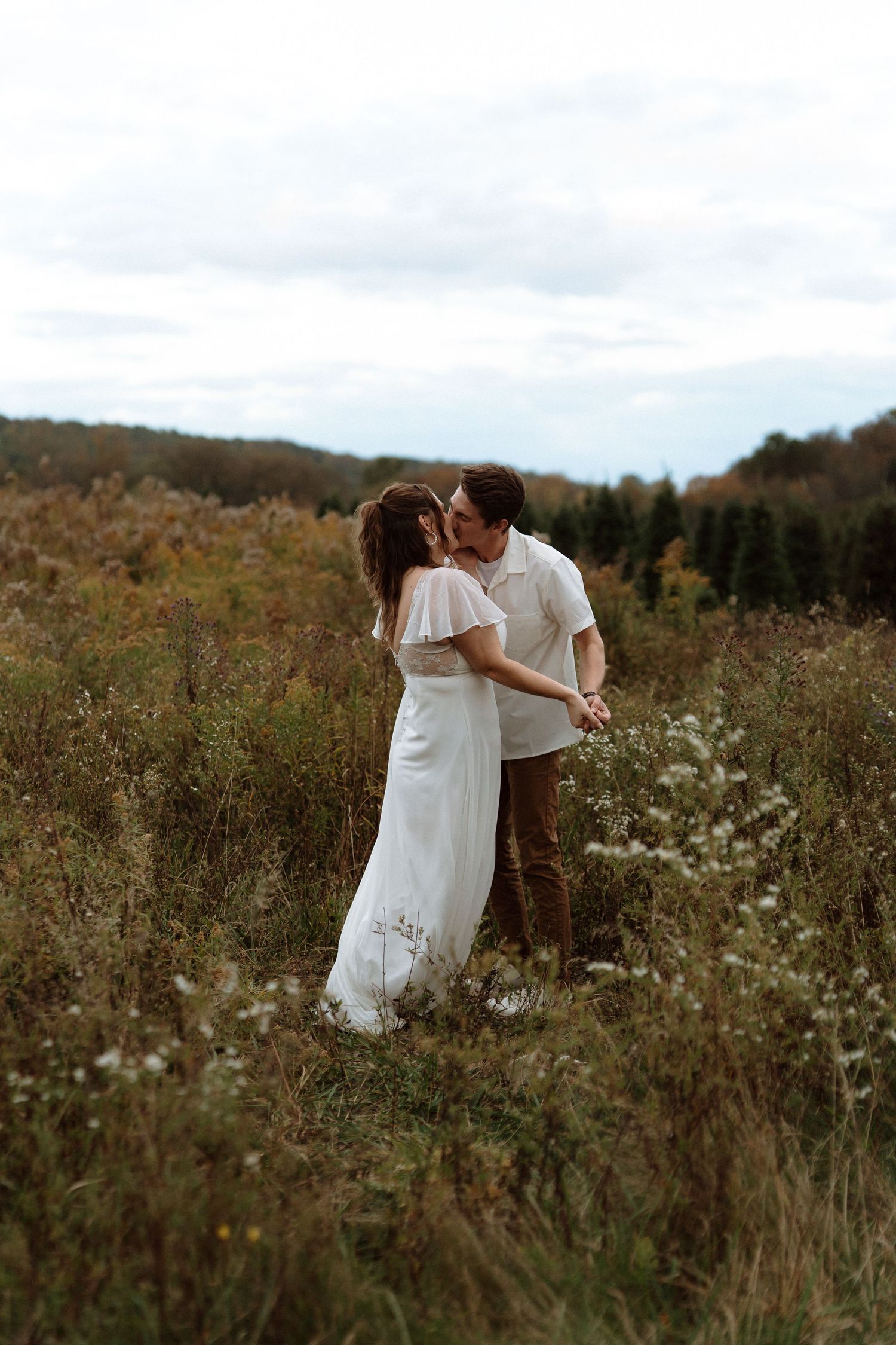 A couple embraces romantically in a wildflower meadow during a sunset photo session.