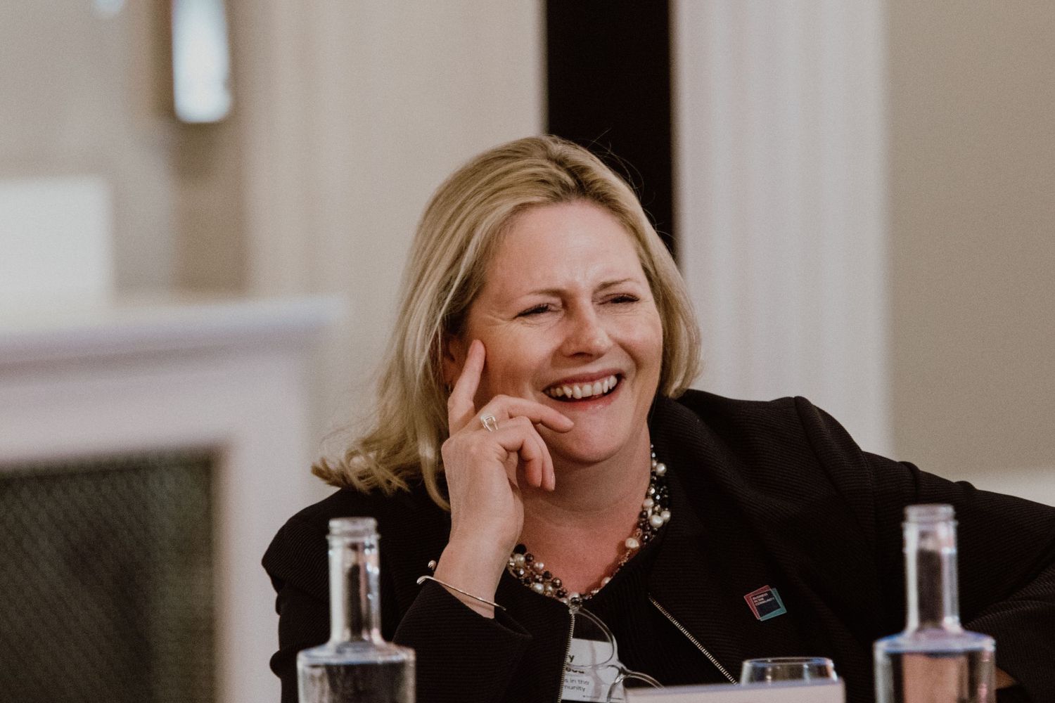 Professional looking relaxed and laughing during a business meeting with water bottles on the table.