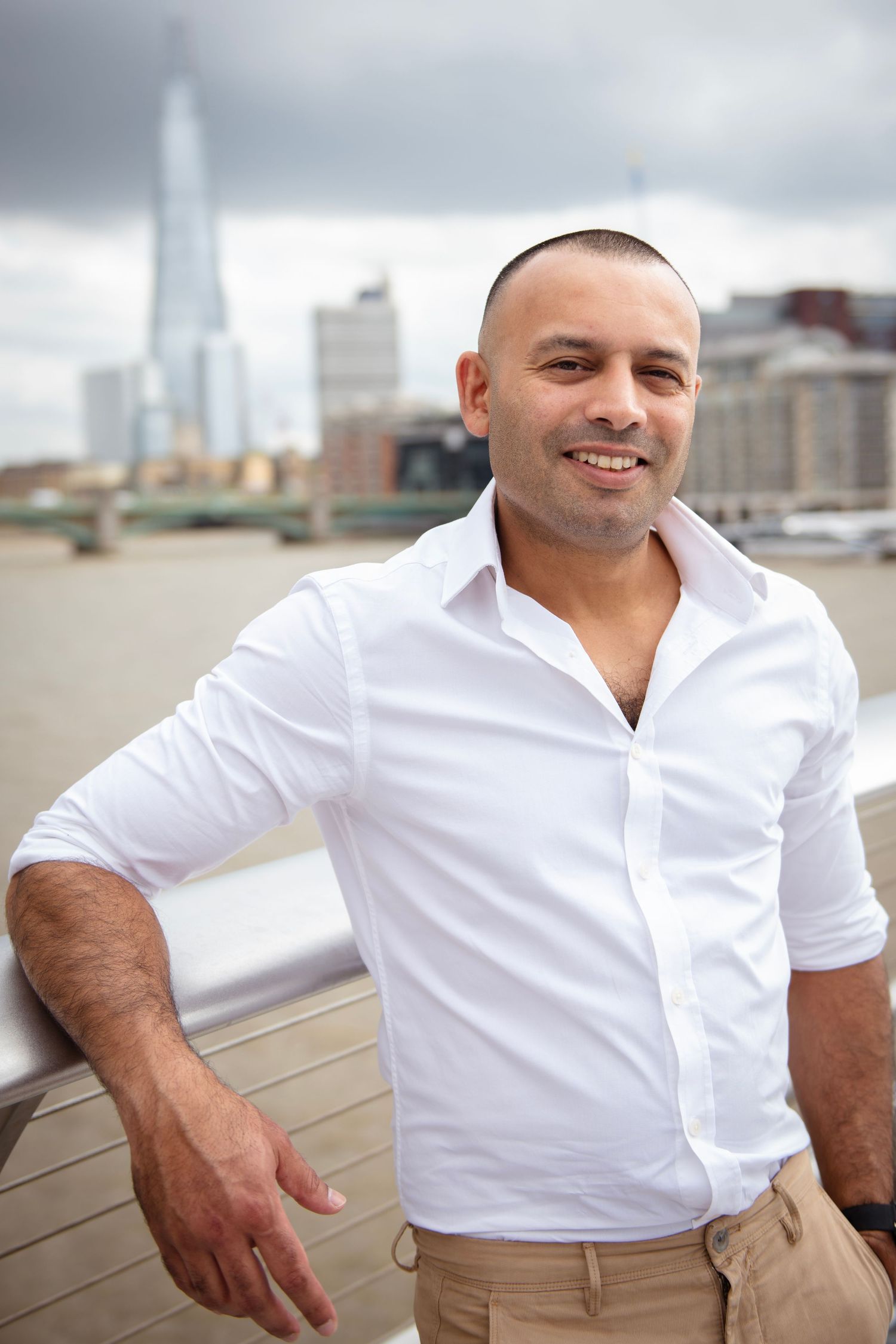 Someone in a crisp white shirt sits casually on a wooden deck with an urban skyline visible in the background.