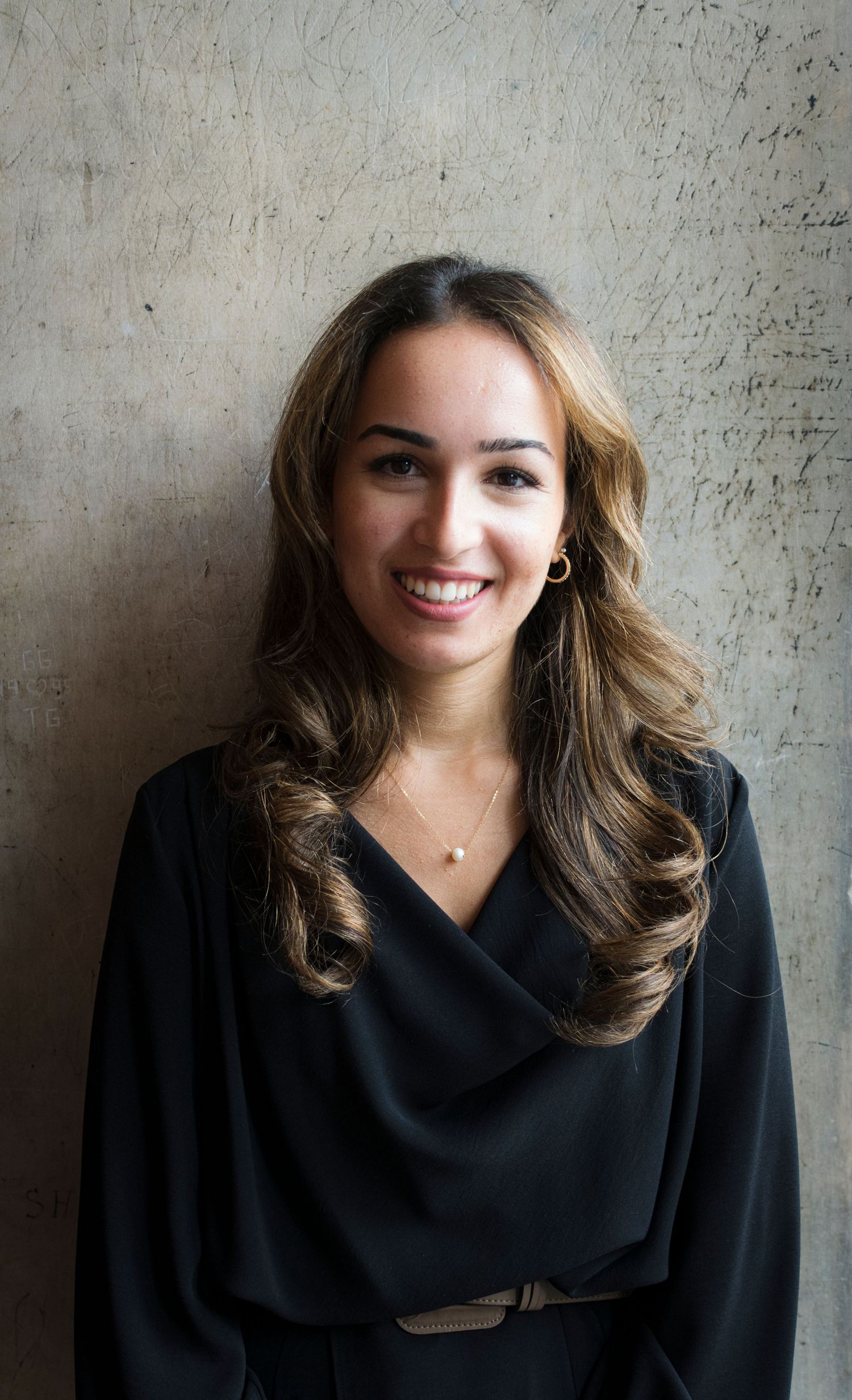 Professional portrait series showing a person in a black draping shawl against a textured wall background.