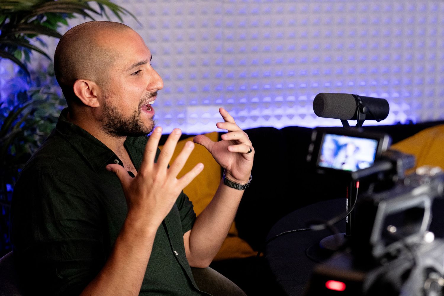 Content creator gesturing while recording content in studio with microphone and lighting setup.