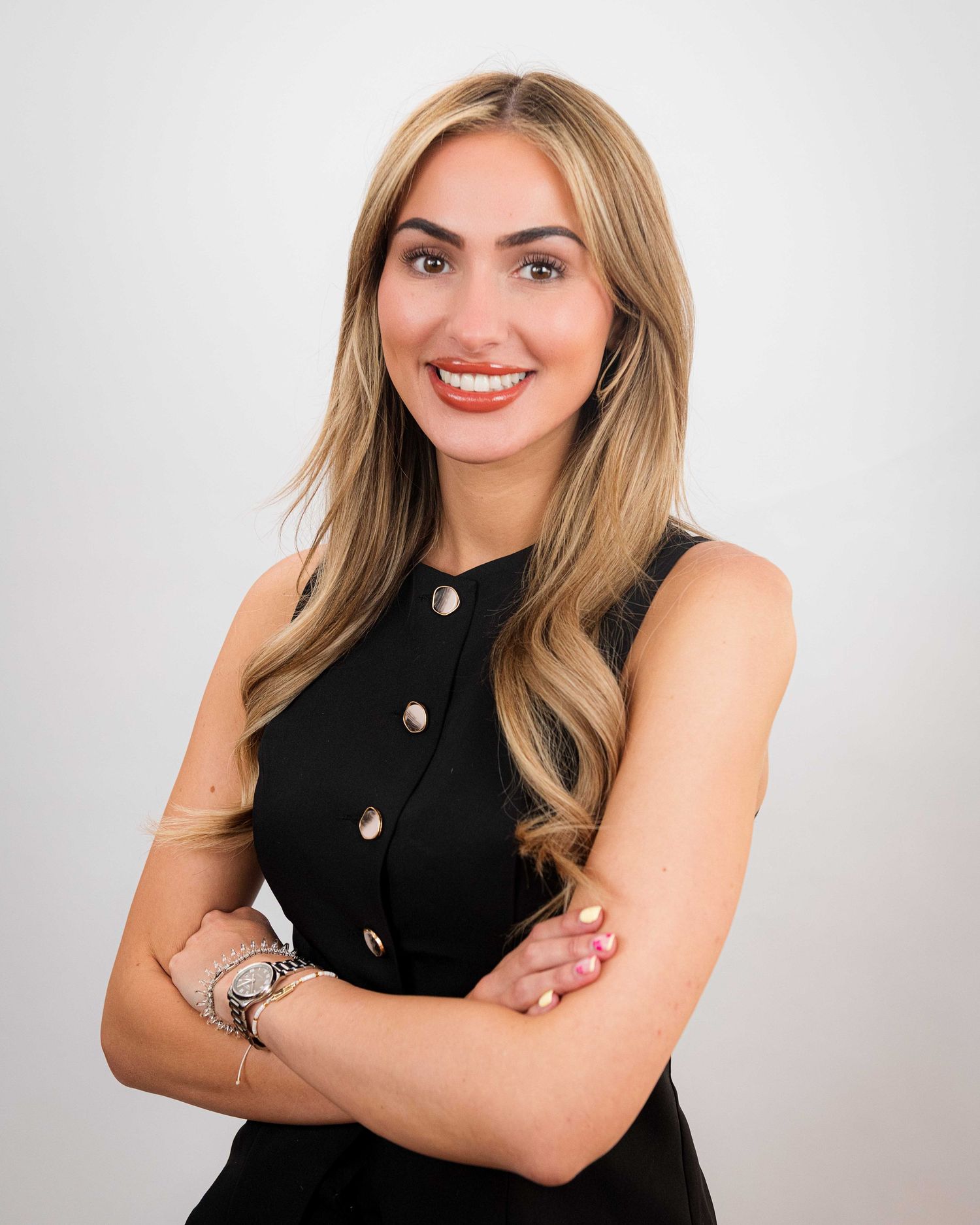 Professional portrait against white background wearing black button-up sleeveless top.