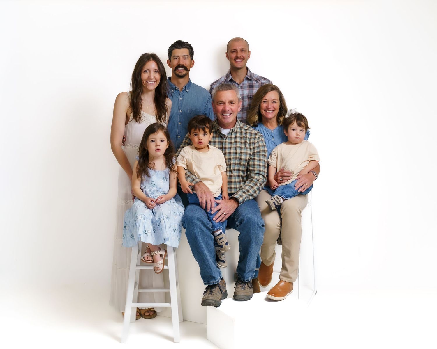 Extended family portrait with grandparents, two adult children, and three young grandchildren in studio.