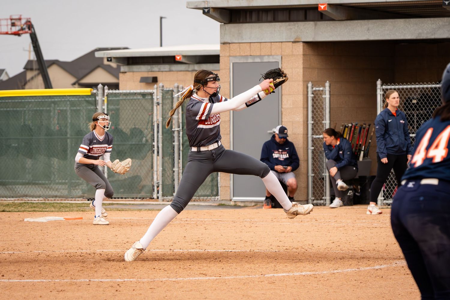 Softball pitcher winds up for powerful pitch delivery during a competitive game.