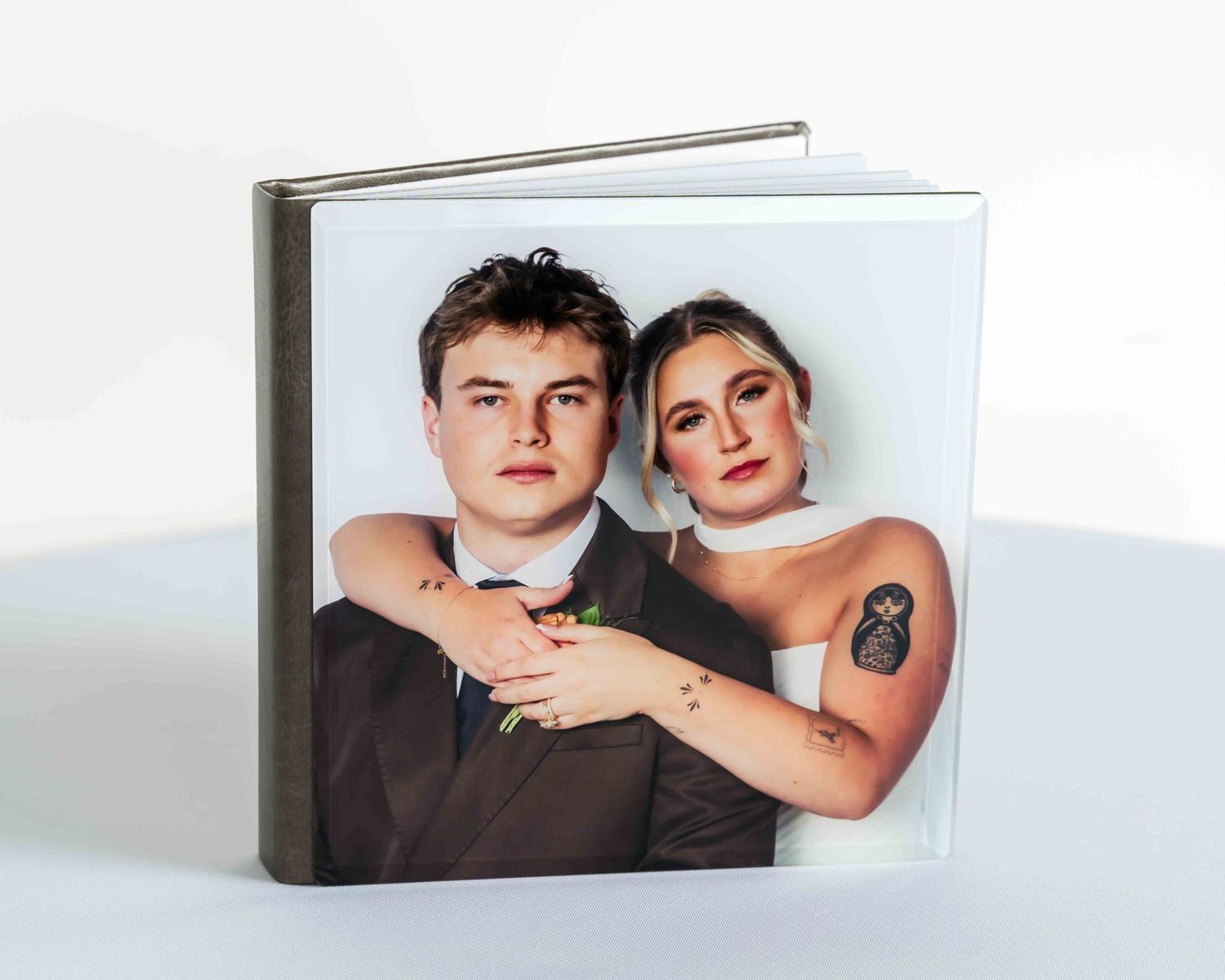 Square wedding photo book with a couple portrait cover, groom in suit and bride in white dress with tattoo.
