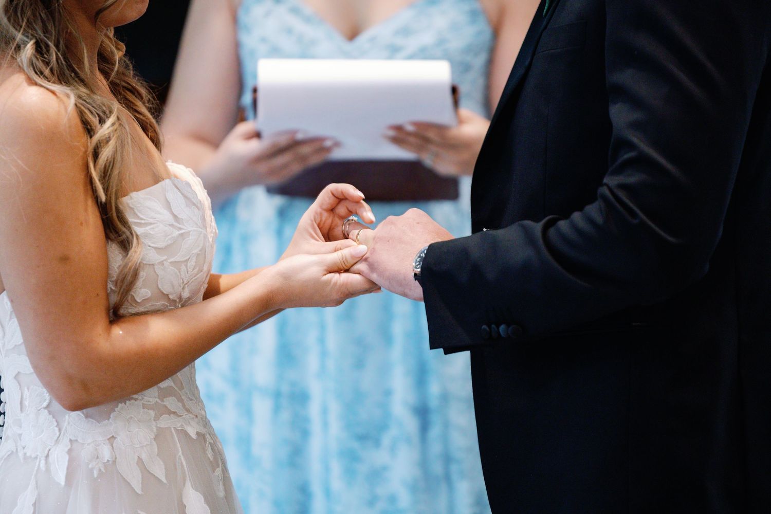 Close-up shots of a wedding ceremony with hands exchanging vows under beautiful floral decorations.