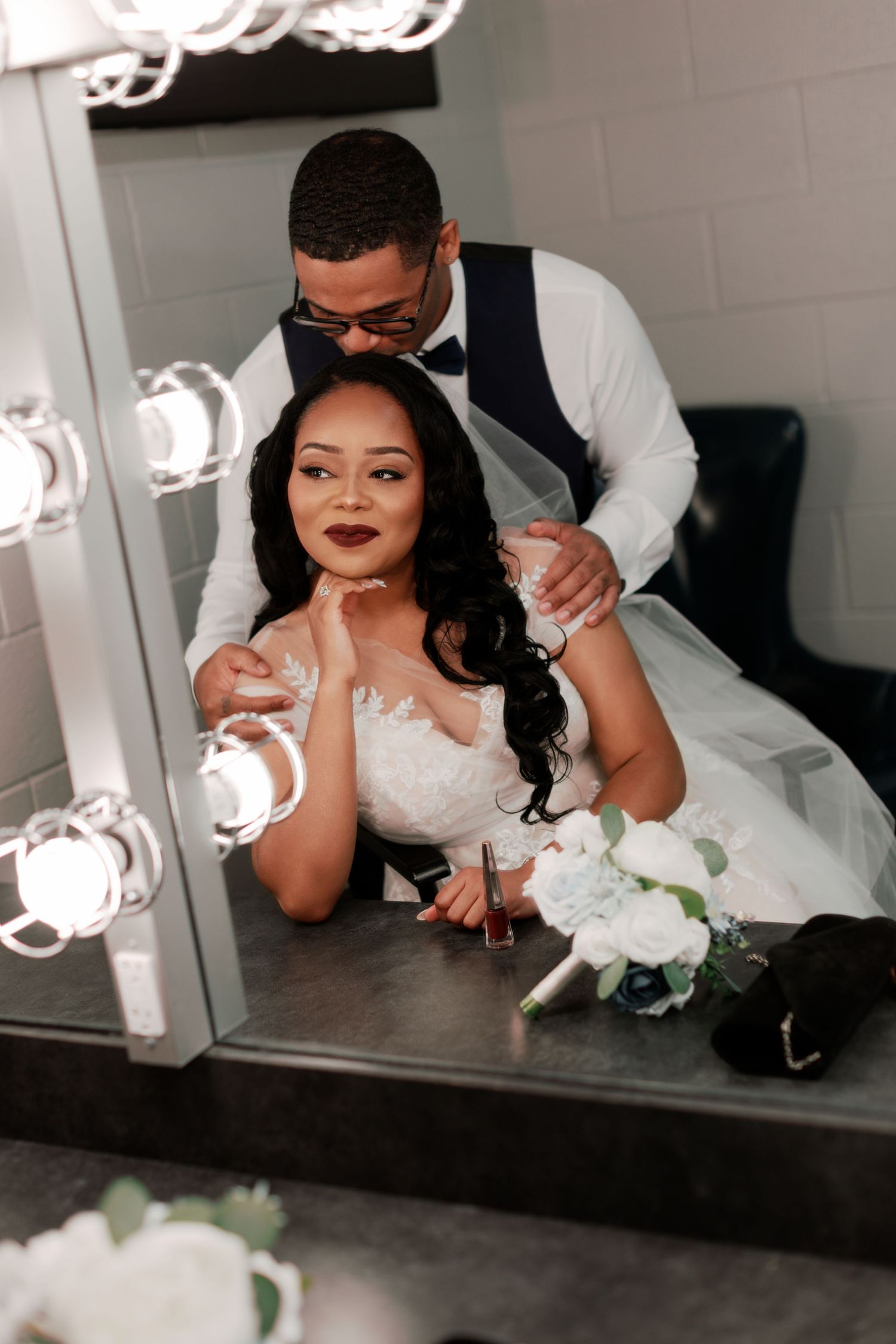 Wedding day preparations with bride looking in mirror and white floral bouquet.