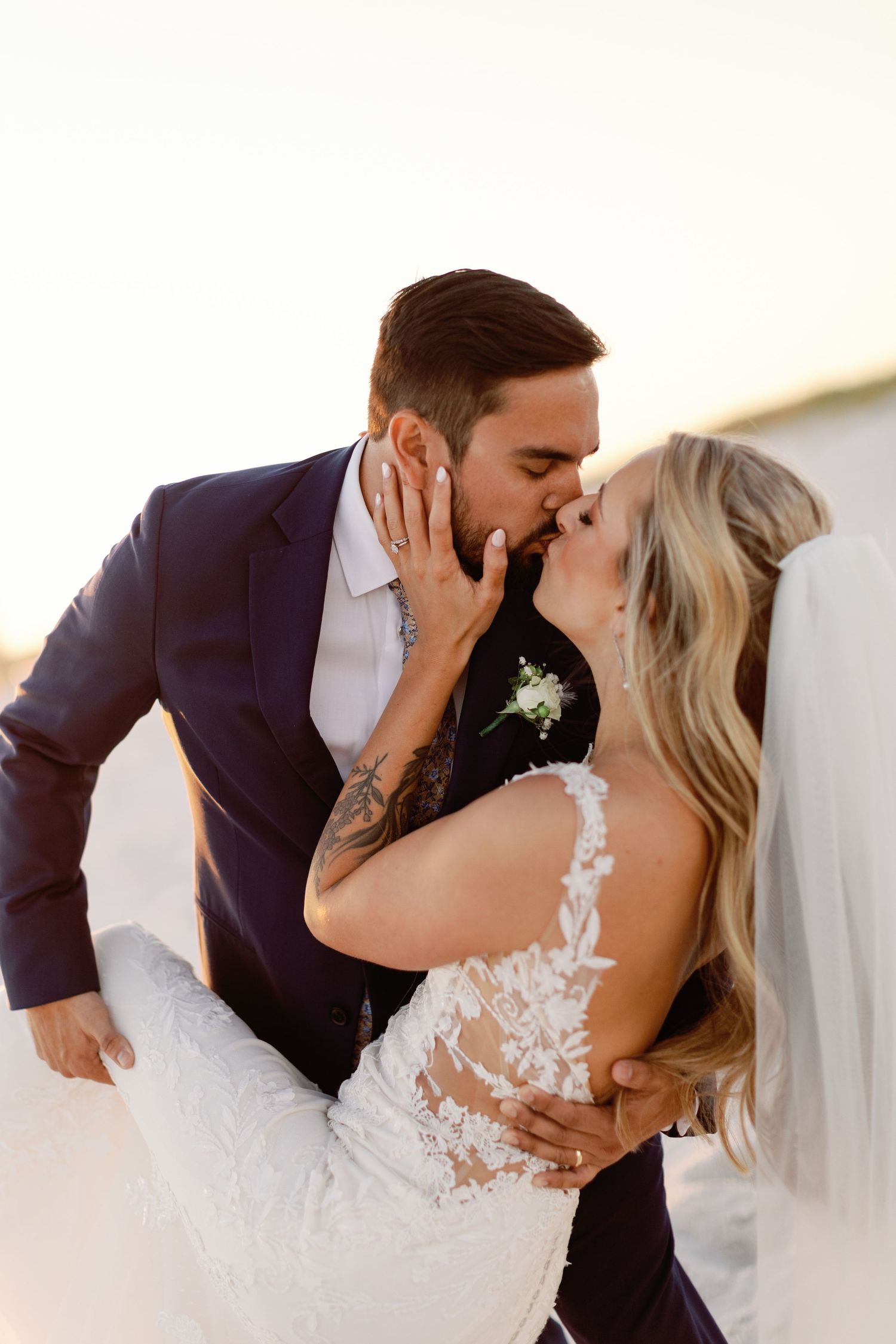 A romantic wedding couple shares a passionate kiss on the beach.
