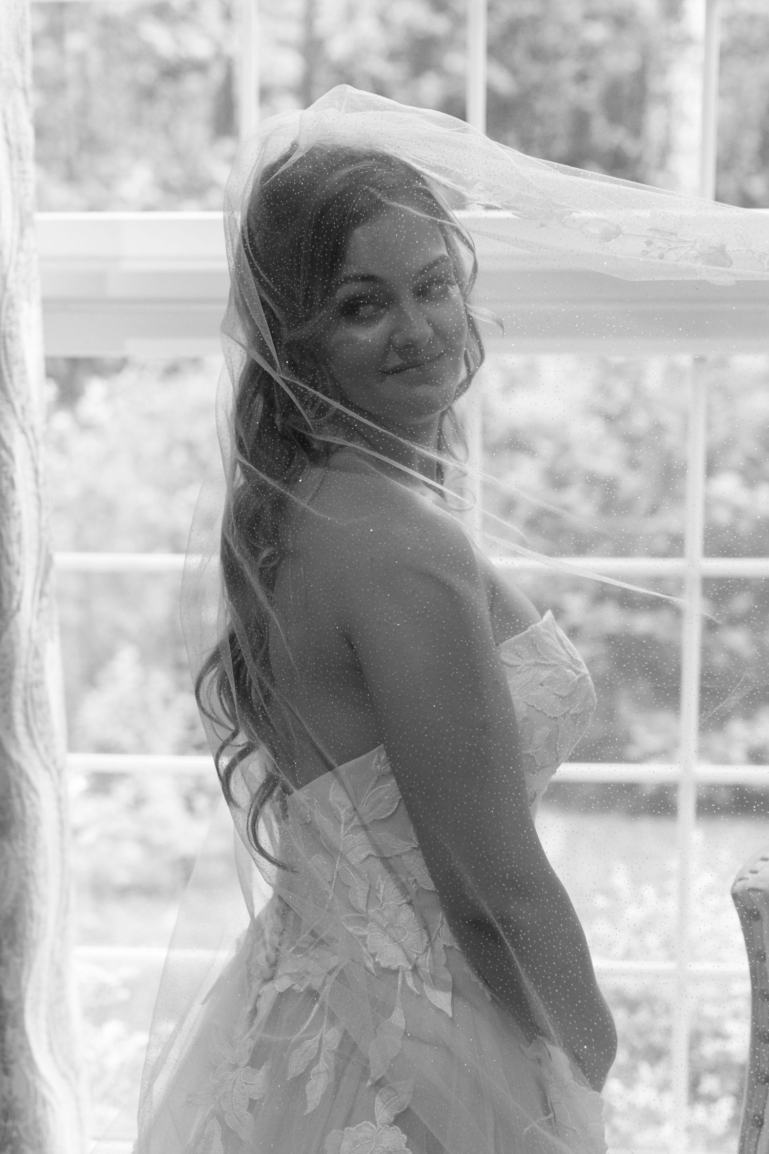 Ethereal bridal portraits captured through window light with flowing veil details.