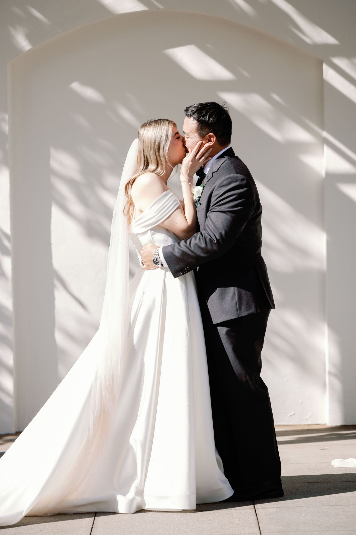 A romantic silhouetted first look between newlyweds in a sun-drenched hallway.