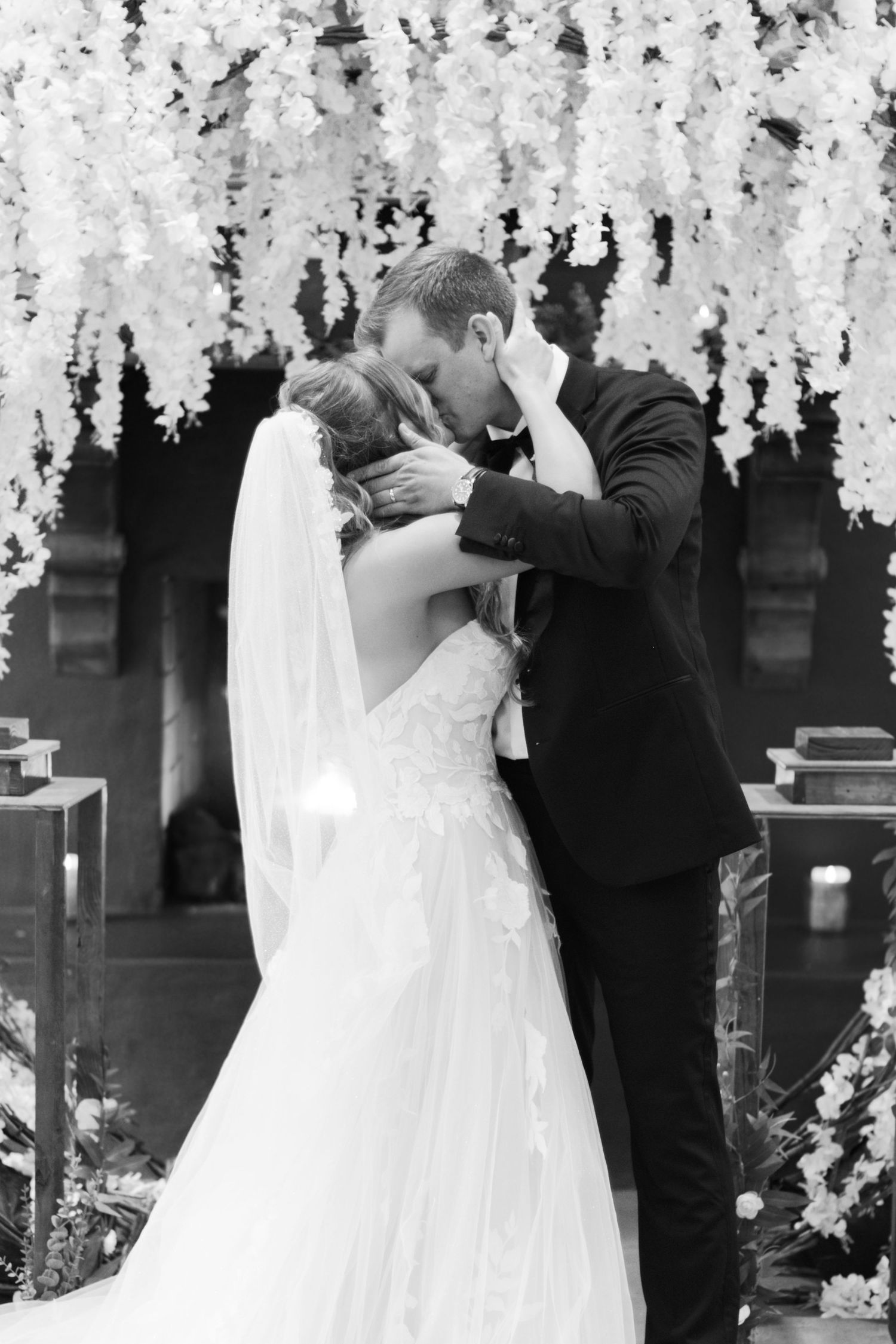 Black and white photos of a wedding ceremony beneath flowing white floral arrangements.