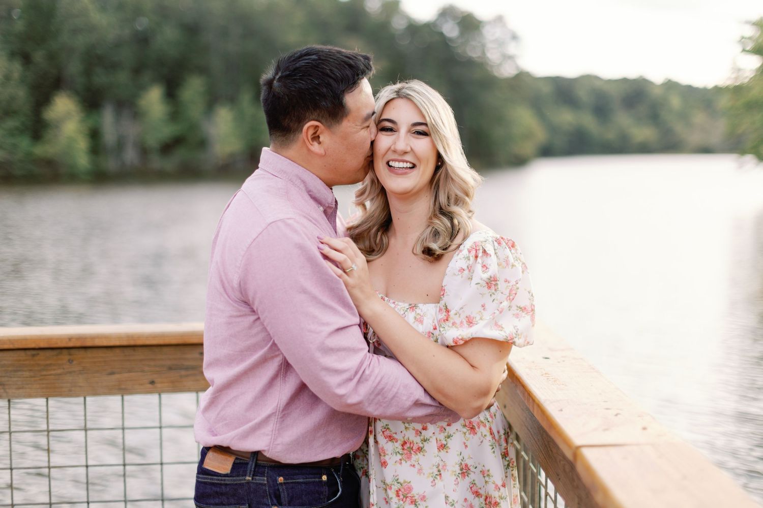 Romantic couple sharing affectionate moments on a wooden deck by the water during sunset.