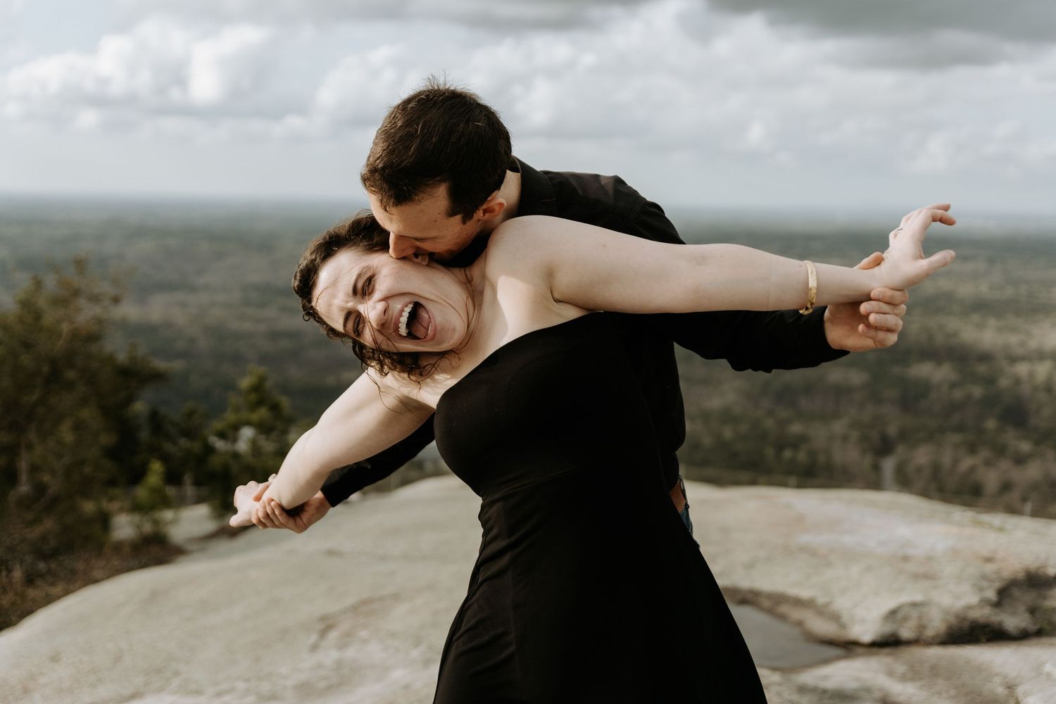Couple enjoying a carefree moment together on a mountaintop overlook.