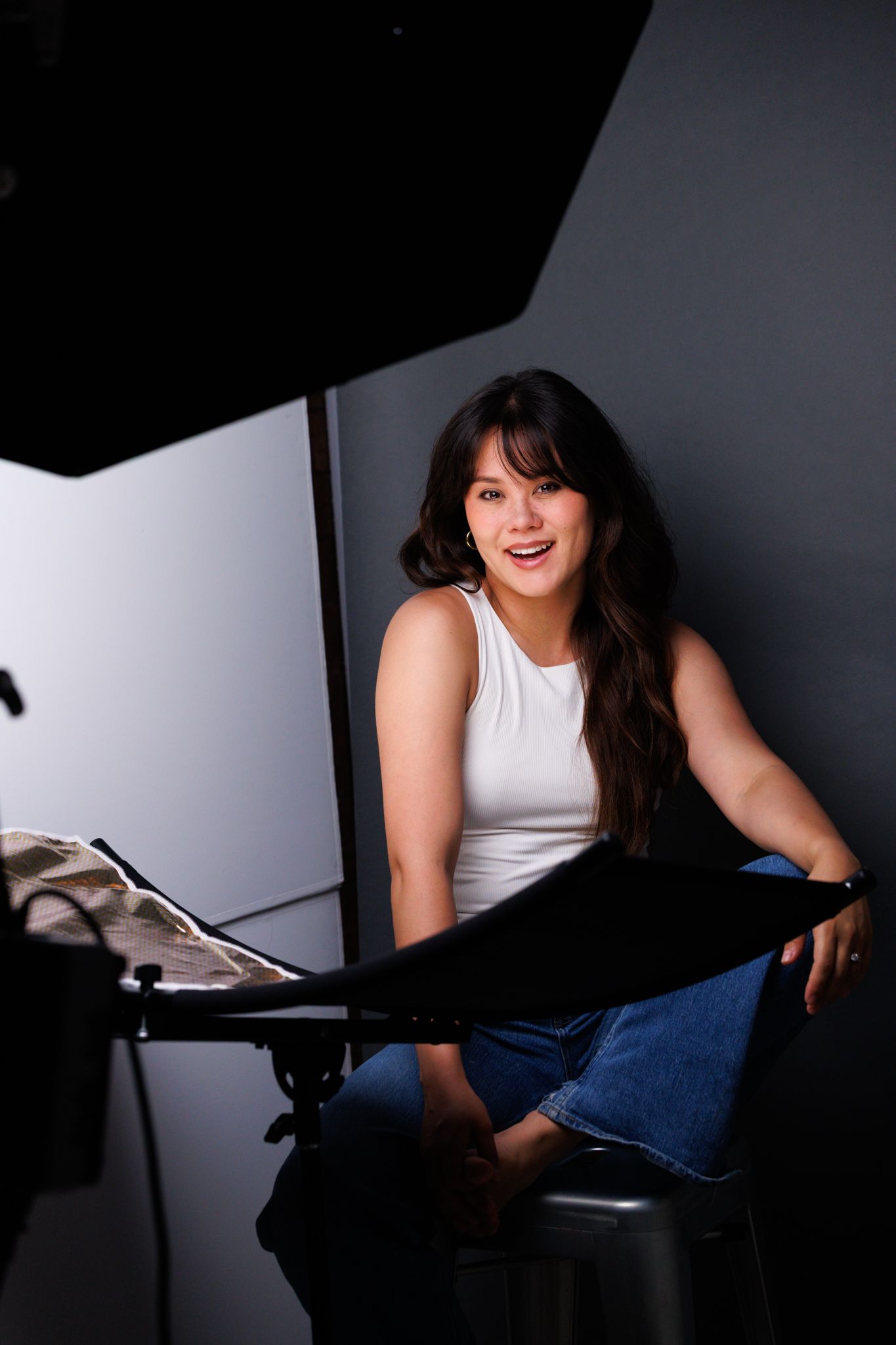 Casual portrait session in studio with moody lighting and dark background.