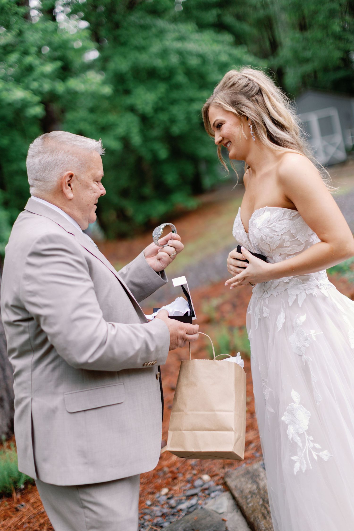 Two people share an emotional gift-giving moment in a wooded outdoor setting.