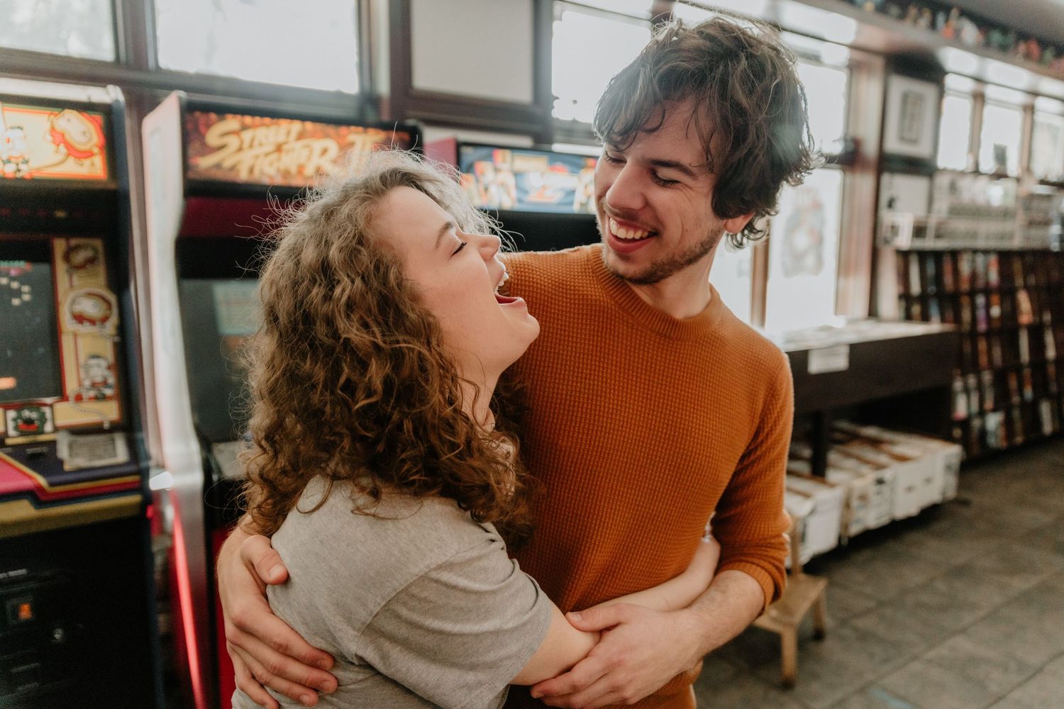 Couple sharing a joyful moment together while embracing in what appears to be a retro arcade or game room.