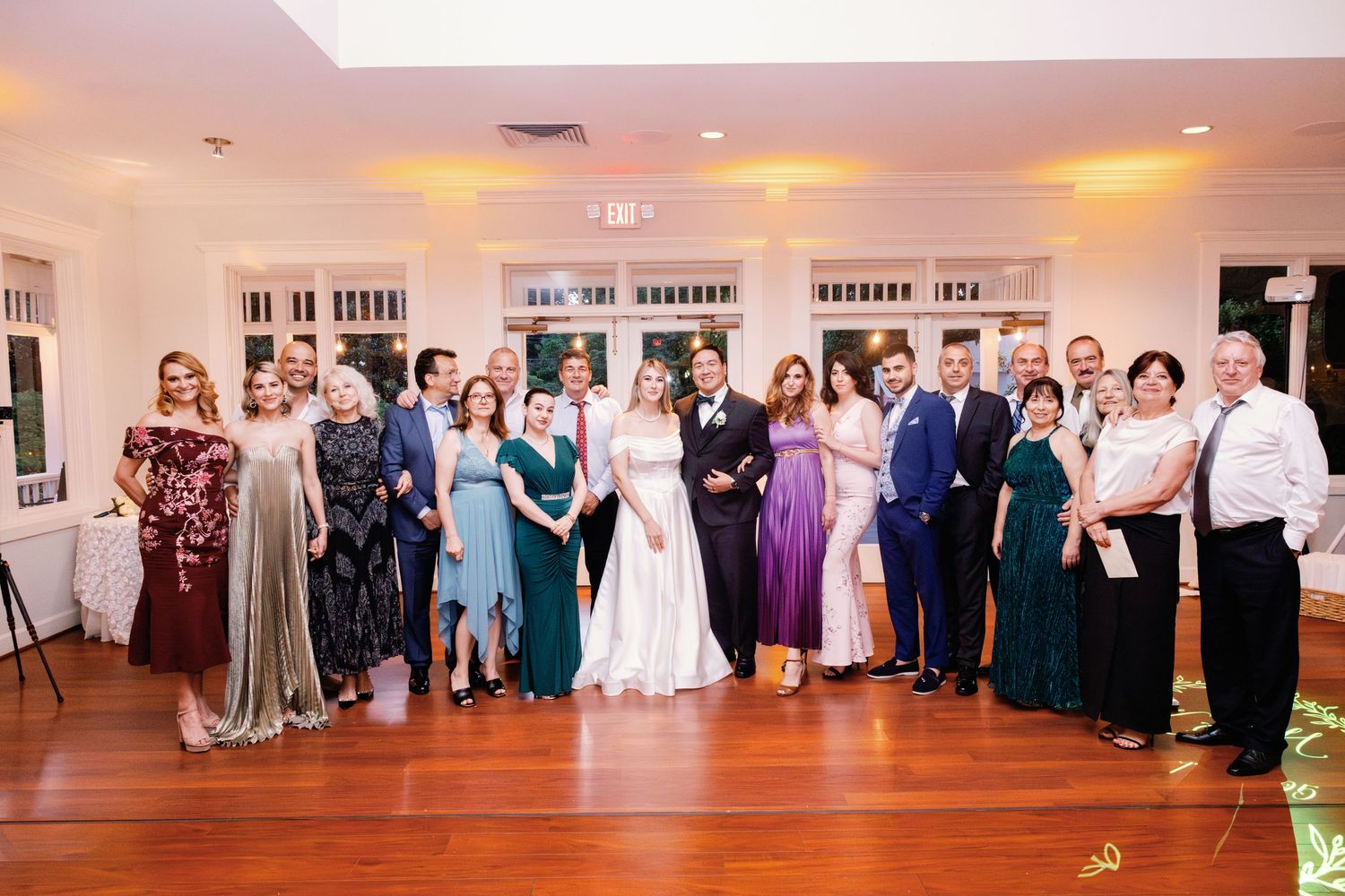 Large wedding reception with guests dancing and celebrating on a wooden dance floor.