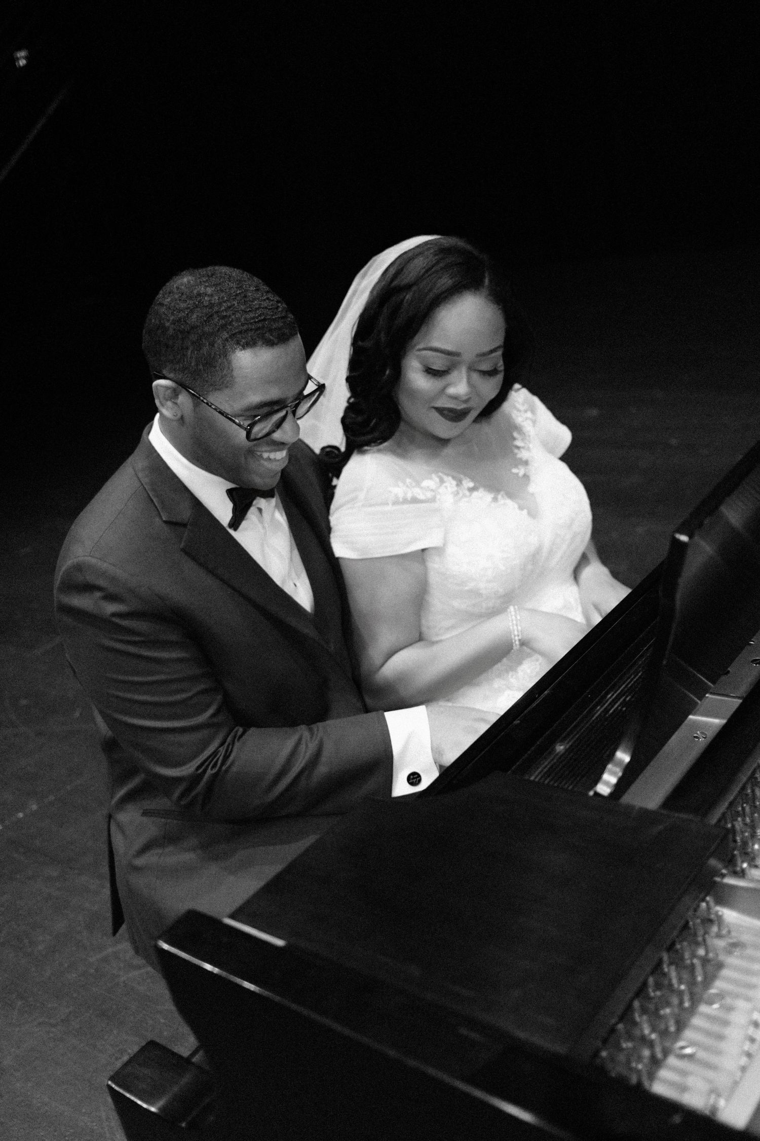 Couple sharing intimate moment at piano during wedding photoshoot.