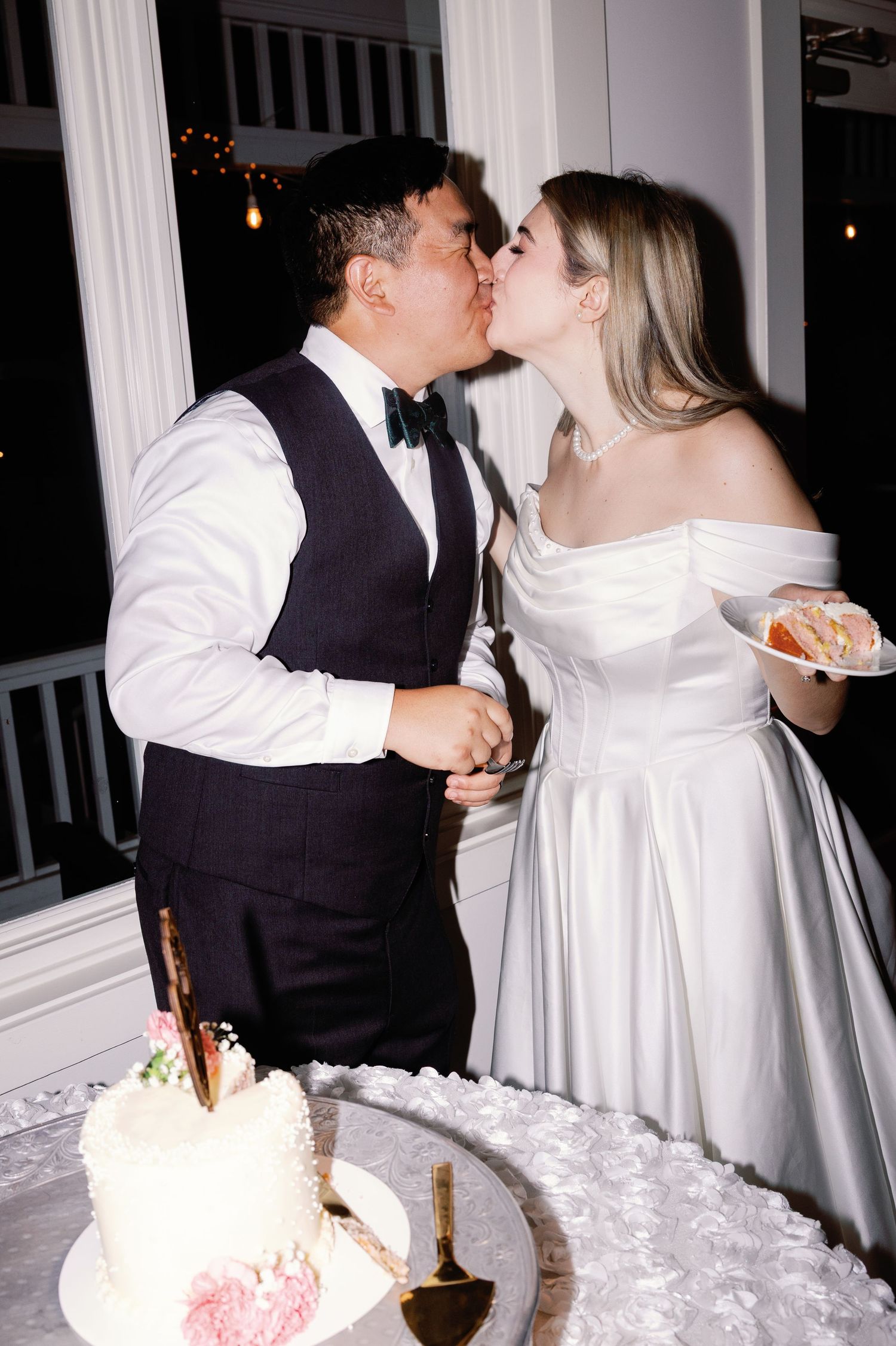 Couple feeds each other wedding cake during their reception celebration.