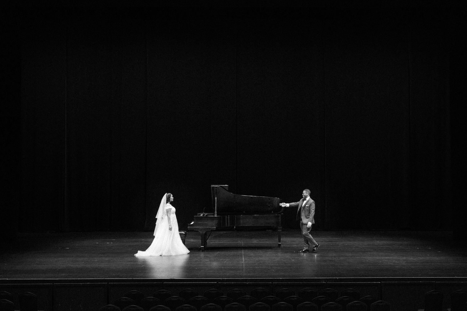 Dramatic black and white wide shot of performers on a minimalist stage.