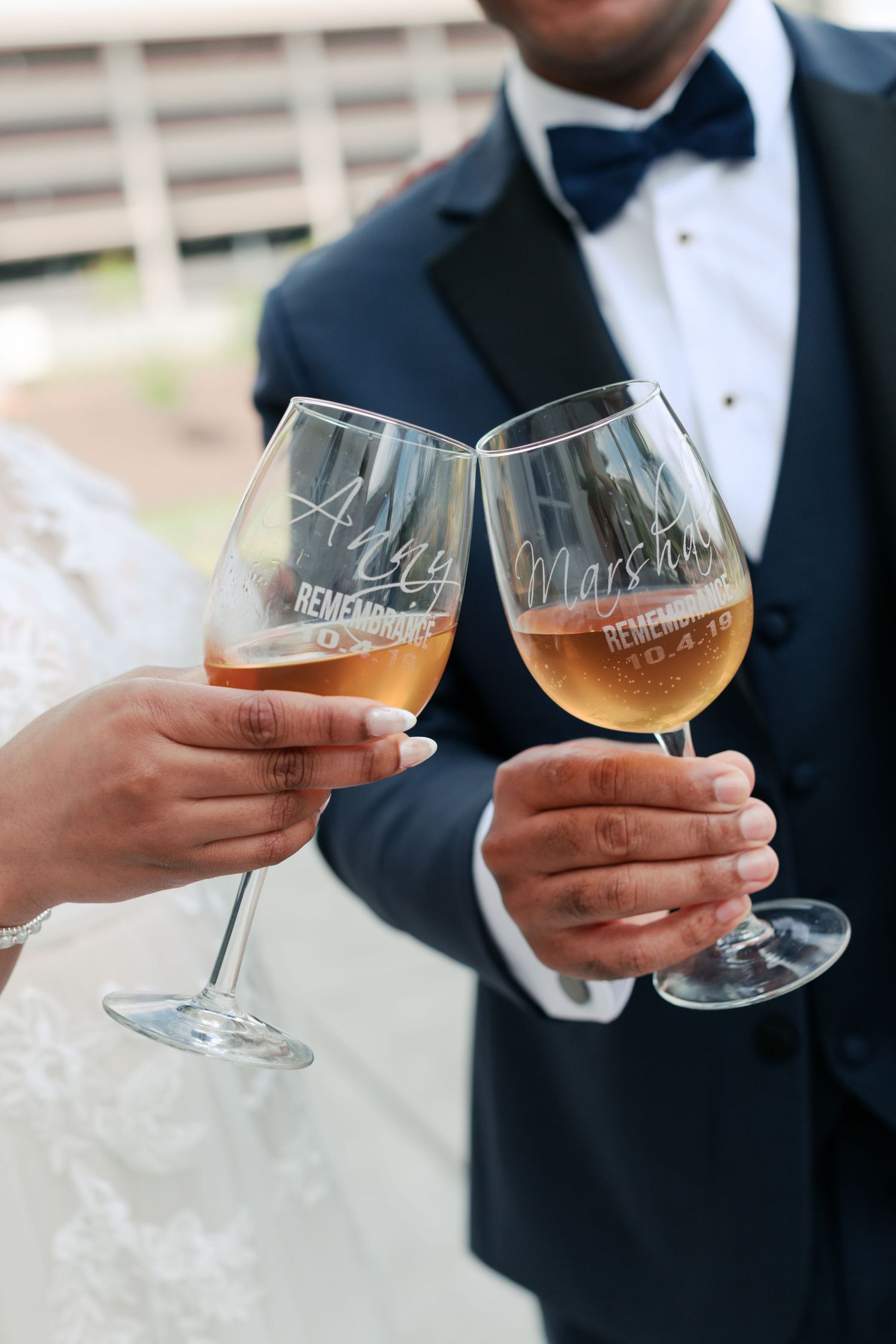 Two wine glasses being toasted with personalized etching at a wedding celebration.
