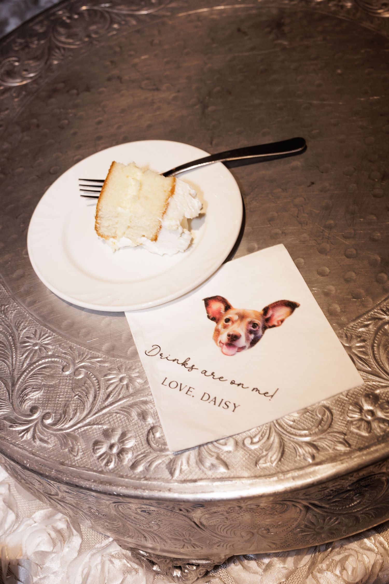 Place cards and slices of wedding cake are arranged on an ornate silver serving platter.