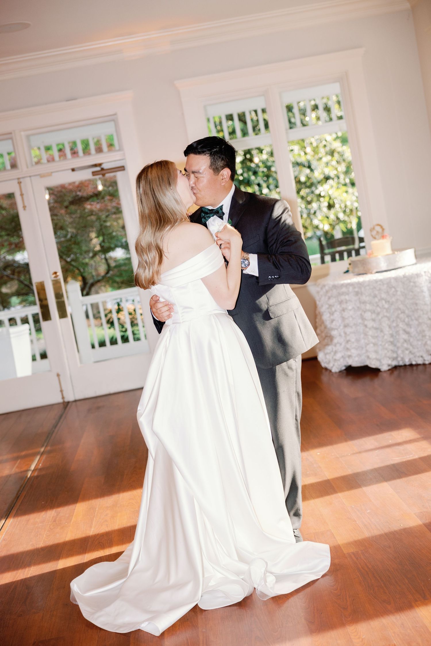 Romantic first dance in sunlit reception room with hardwood floors.