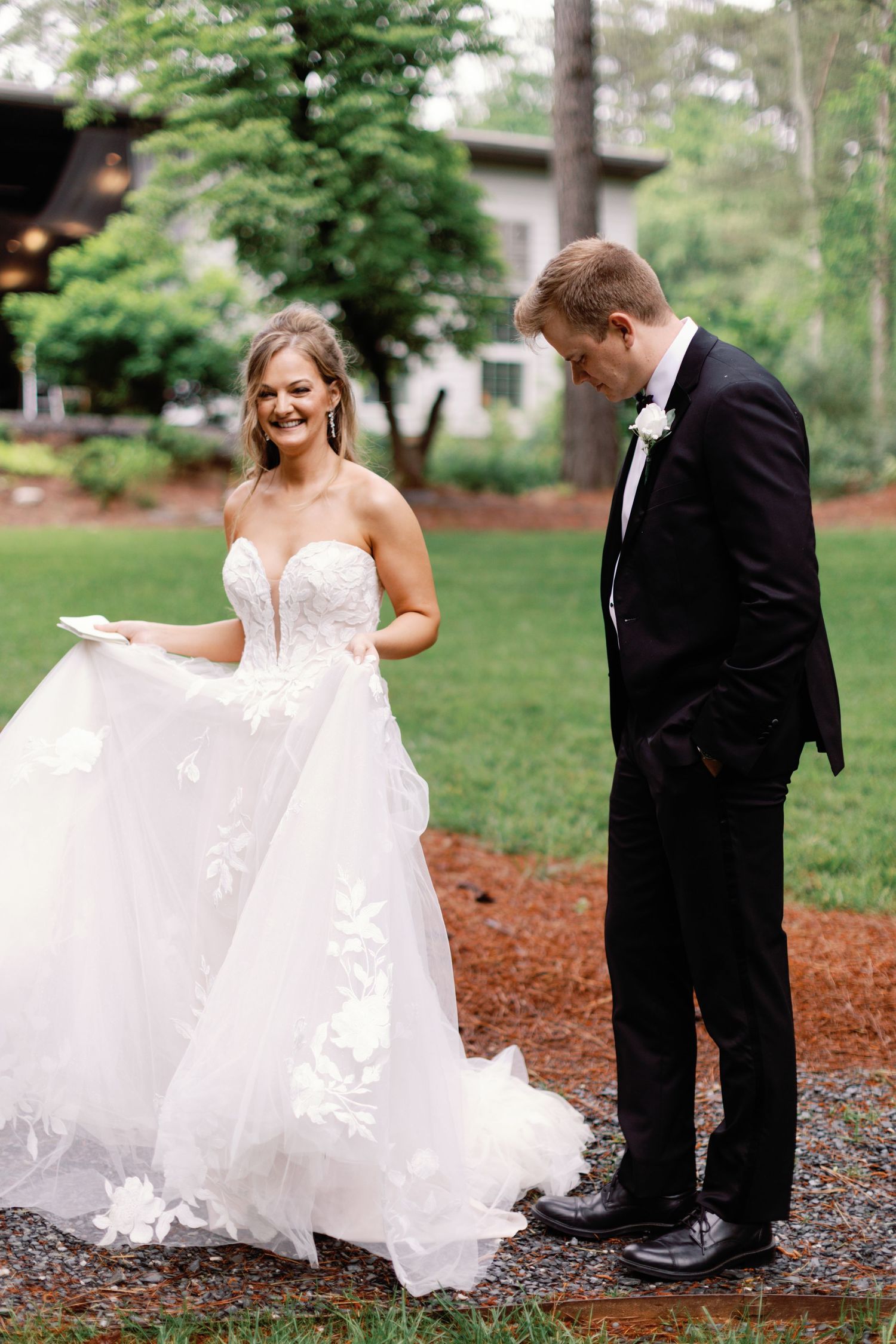 A bride's white dress flows elegantly against the garden backdrop.